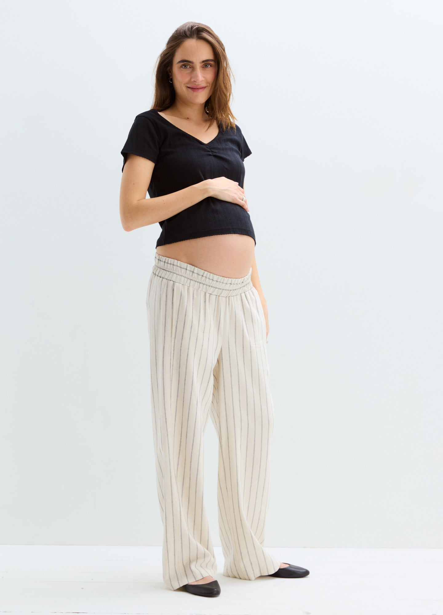 Black short-sleeve maternity sweetheart tee with beige striped wide-leg pants.