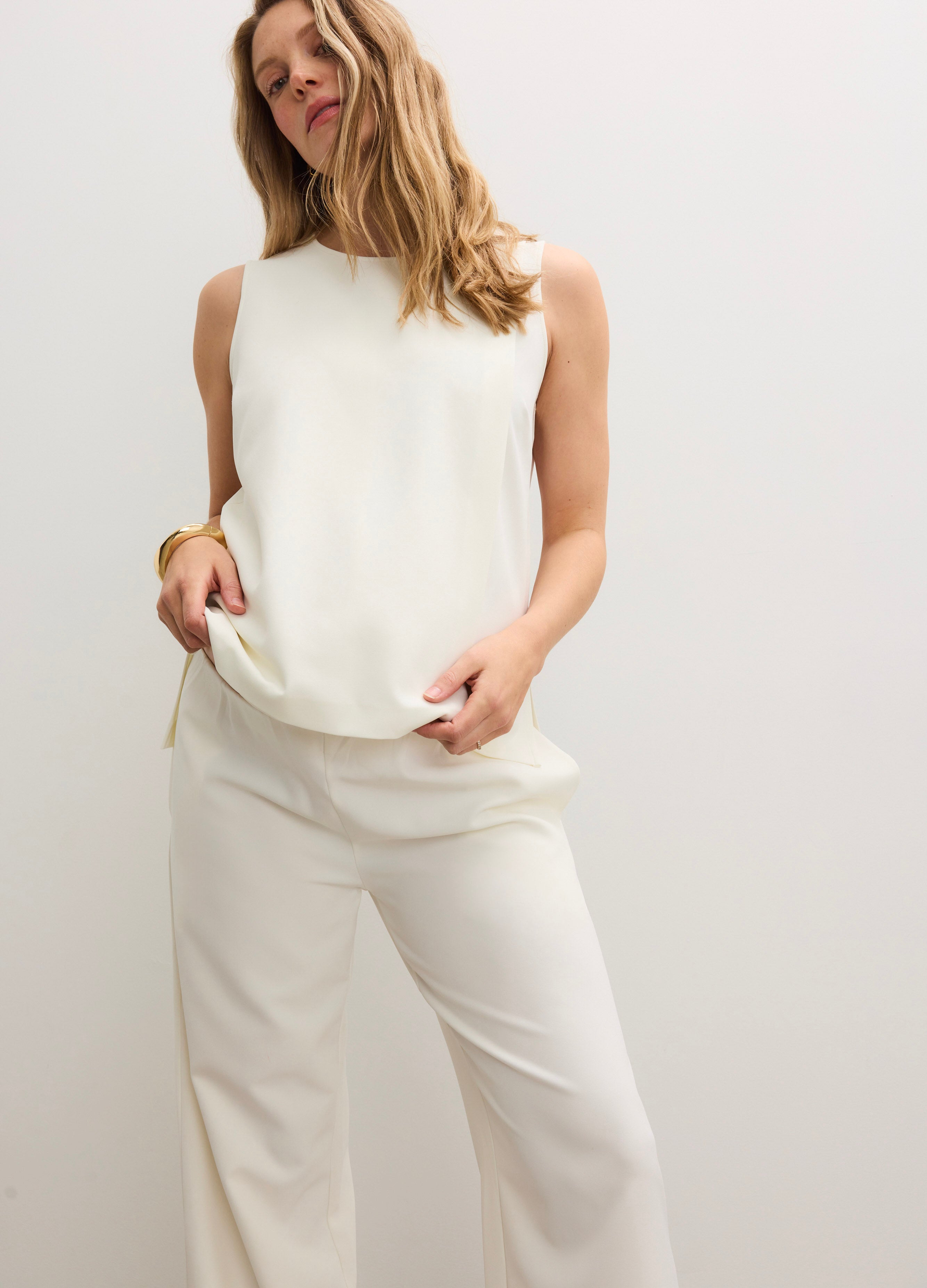 Cream-colored sleeveless nursing tank with a smooth, slightly loose fit, paired with matching wide-leg trousers.
