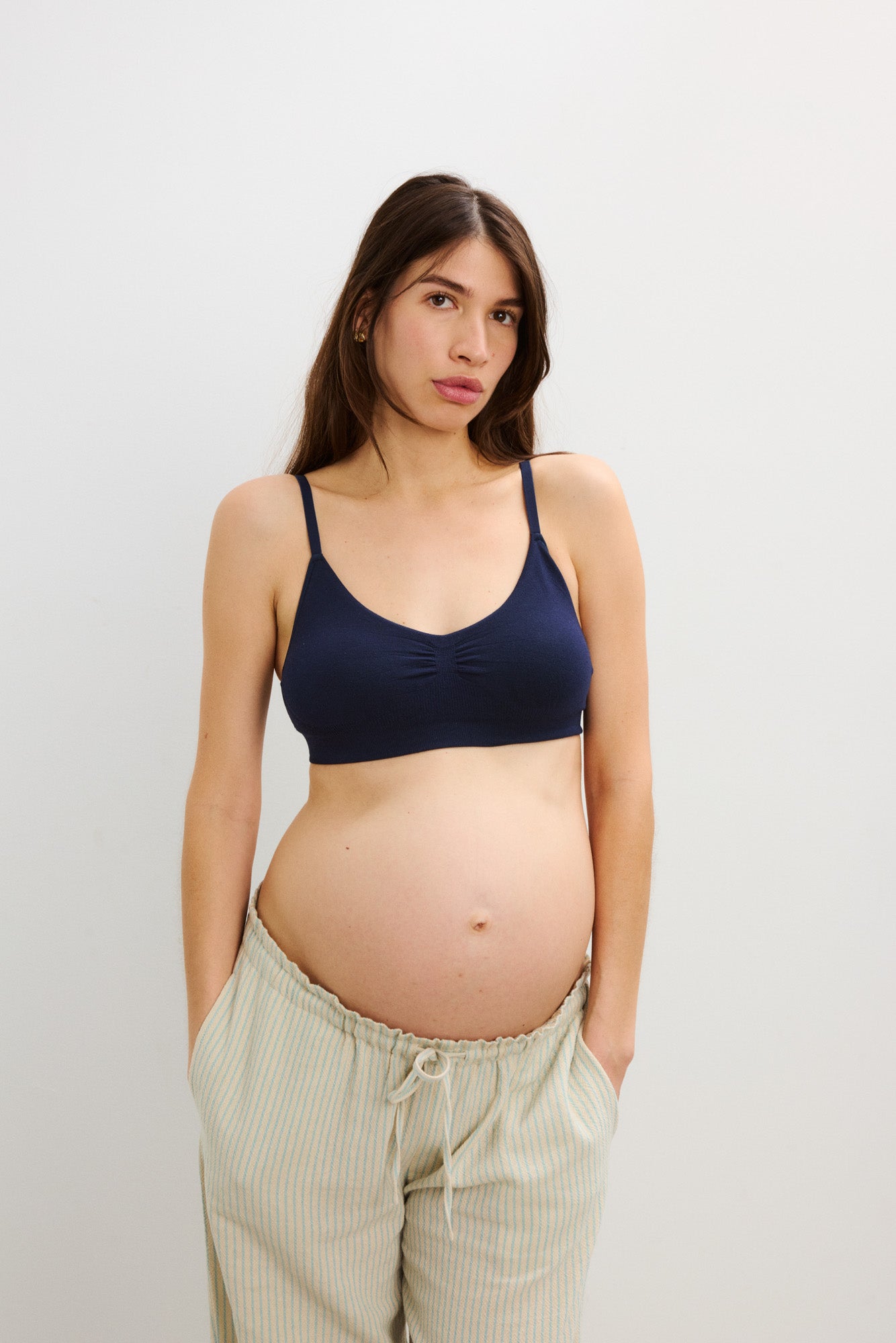 Navy blue soft maternity bra with thin adjustable straps on pregnant woman.