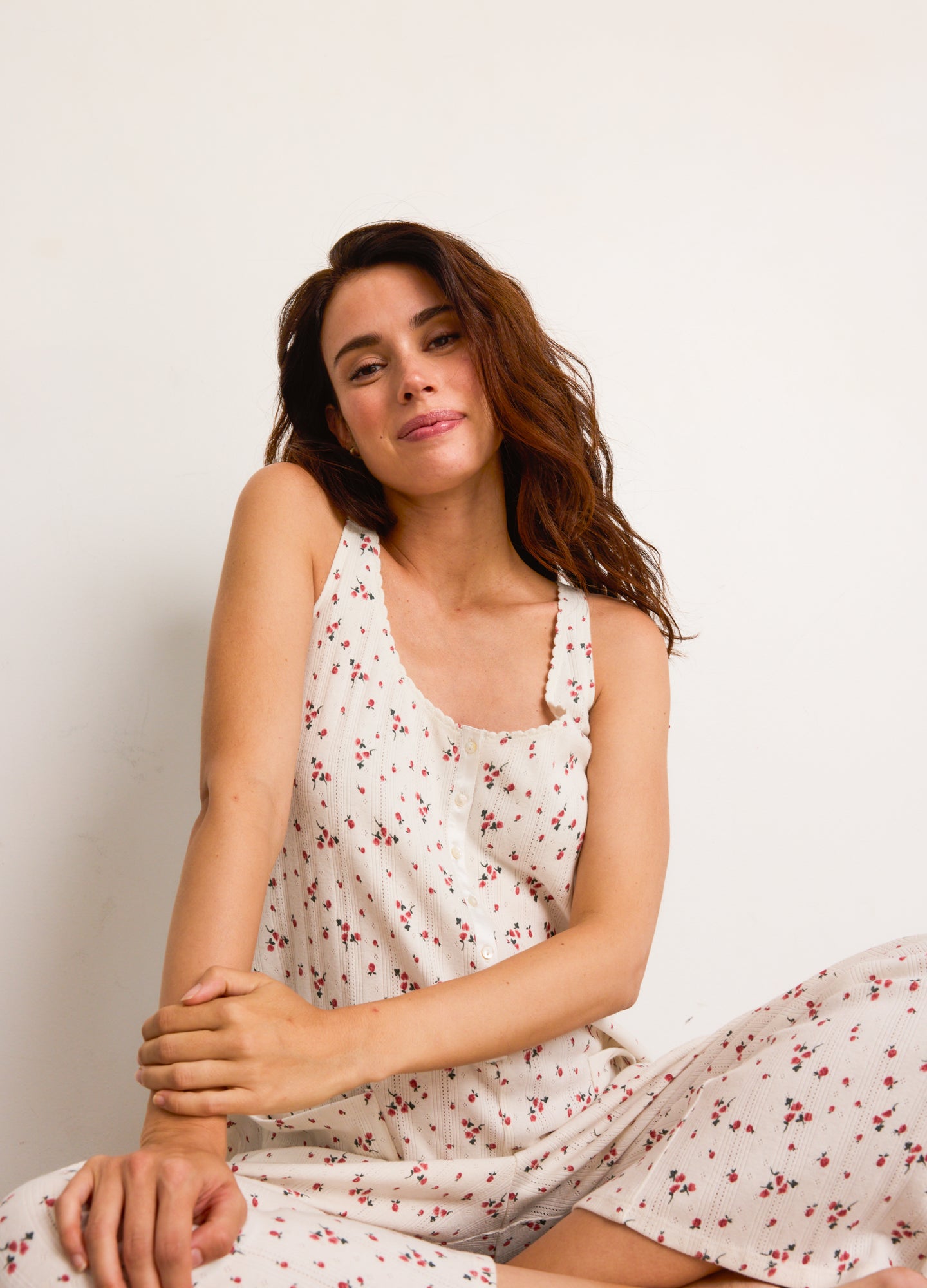 Cream-colored maternity jumpsuit with small red floral print, square neckline, and sleeveless design.