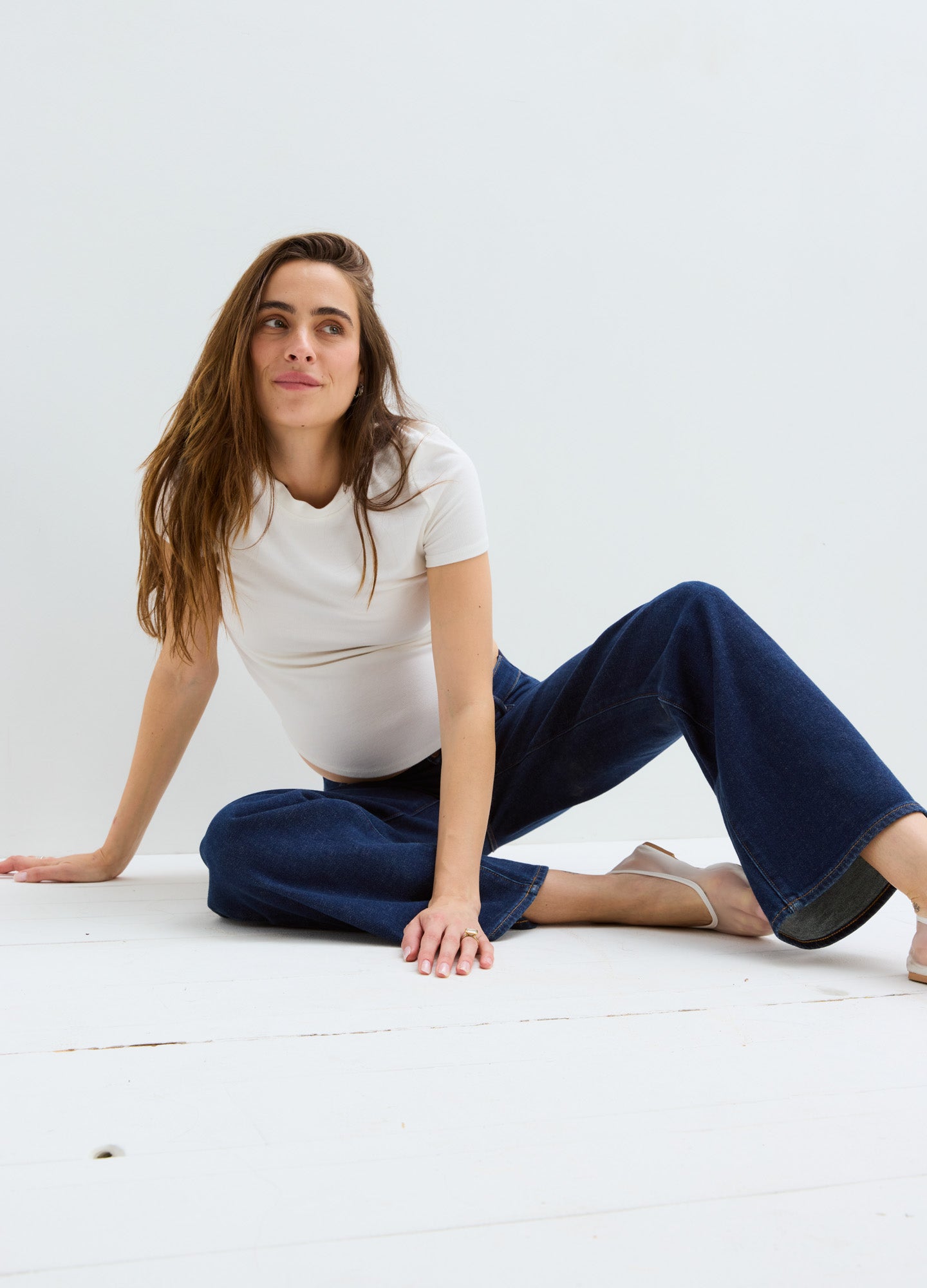 Pregnant woman wearing navy wide-leg maternity jeans with a relaxed fit and elastic waistband paired with a white.