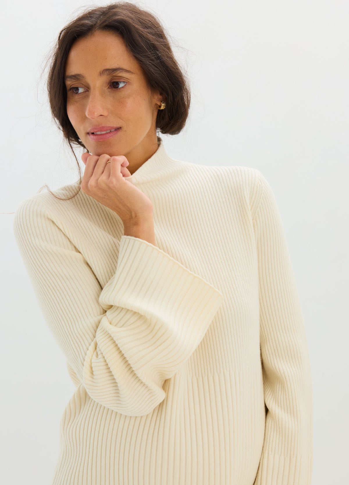Cream-colored soft knit maternity turtleneck sweater with relaxed long sleeves and ribbed cuffs.
