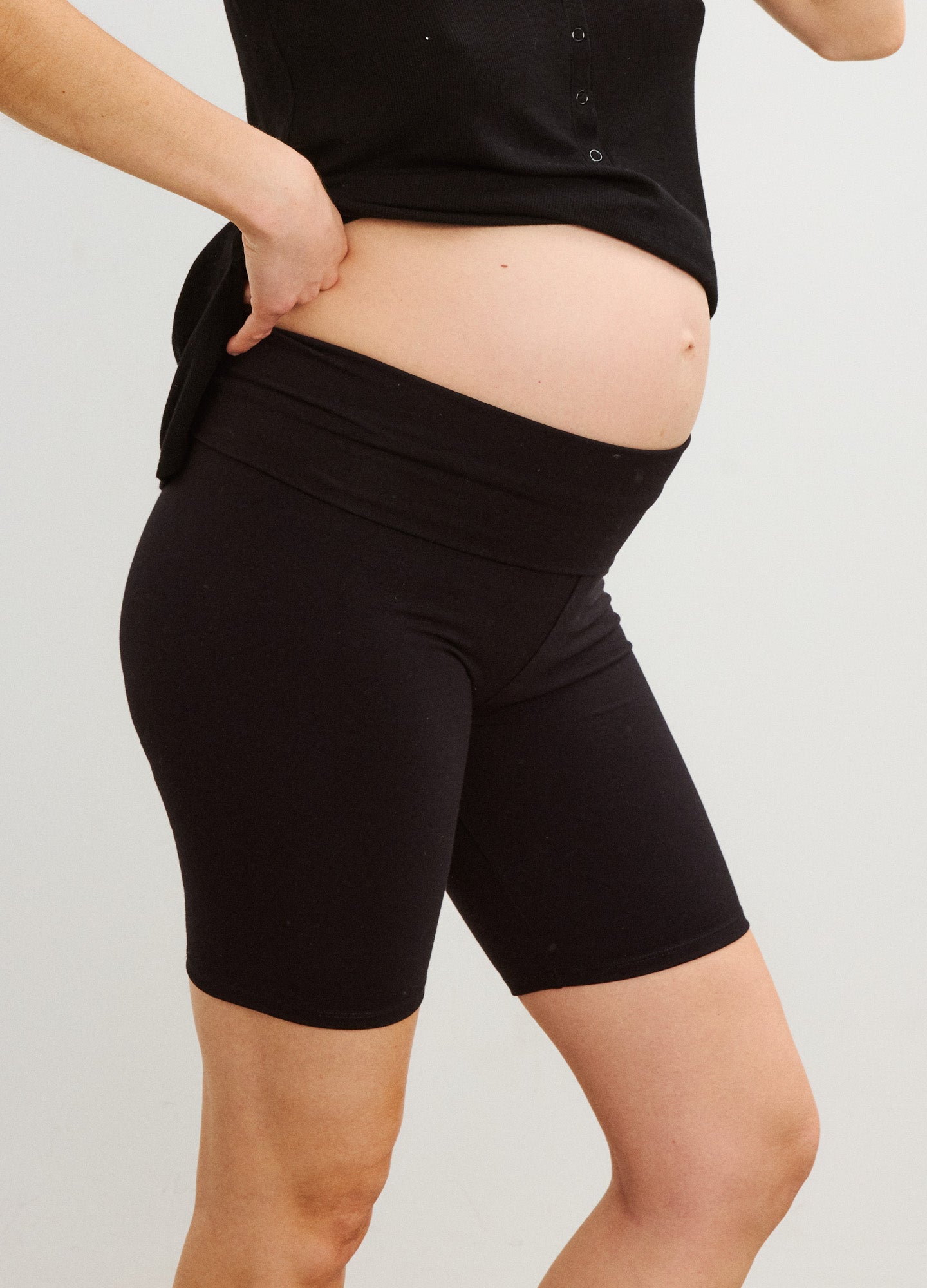 Black stretchy bike shorts with high, supportive maternity waistband covering pregnant belly.
