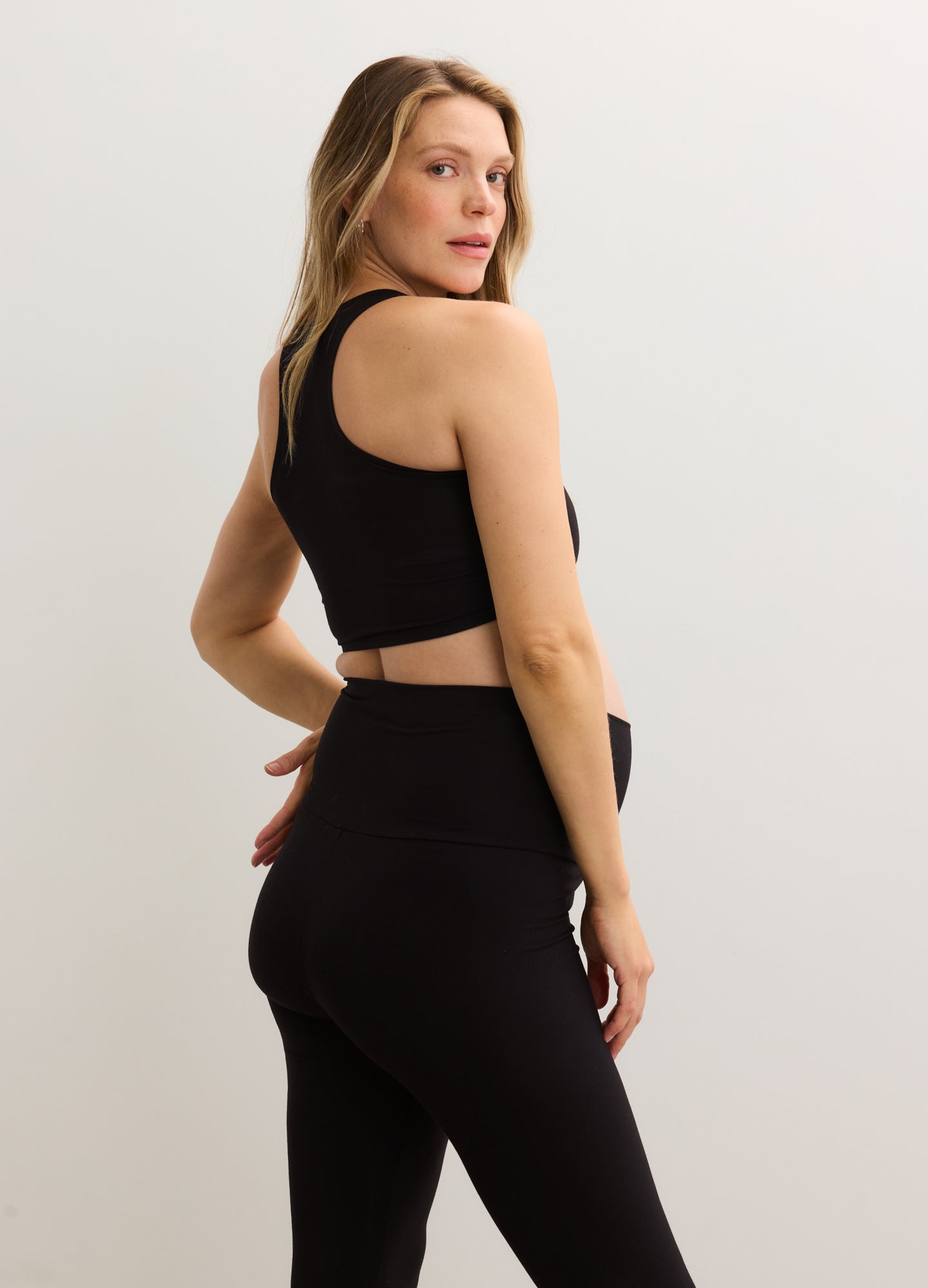 Black stretchy crop racer tank with racerback design, fitted for maternity wear.