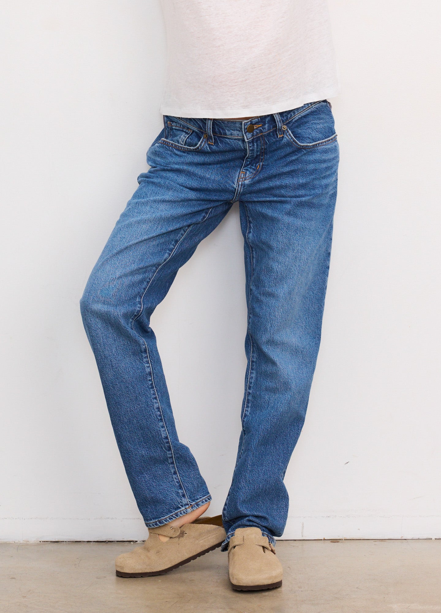 Blue denim maternity boyfriend jeans with relaxed fit and mid-rise waist, worn with beige slip-on shoes.