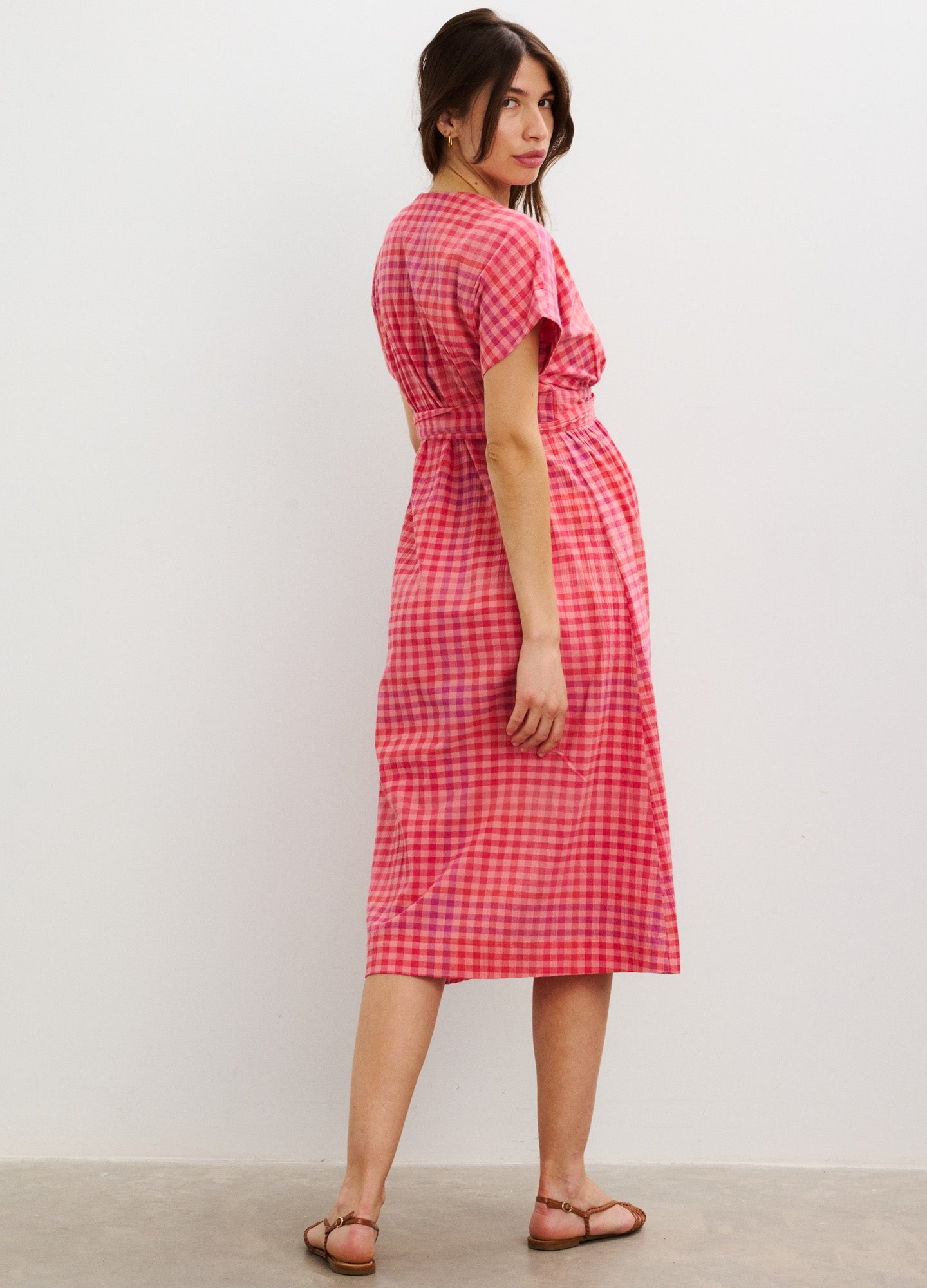 Red and white plaid maternity dress with short sleeves, midi length, and a tie waist.