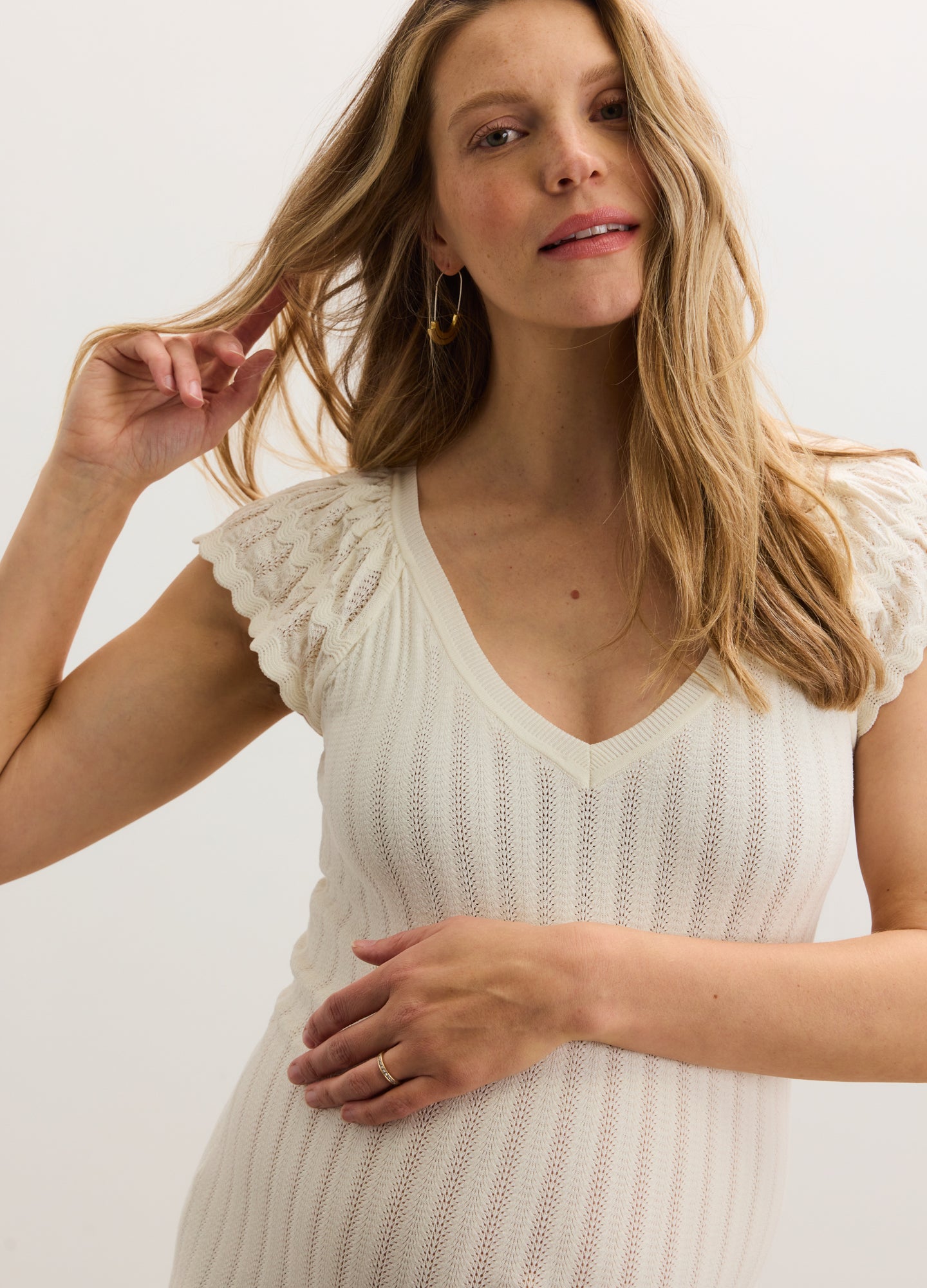Cream-colored ribbed knit maternity dress with short ruffled sleeves and V-neckline.