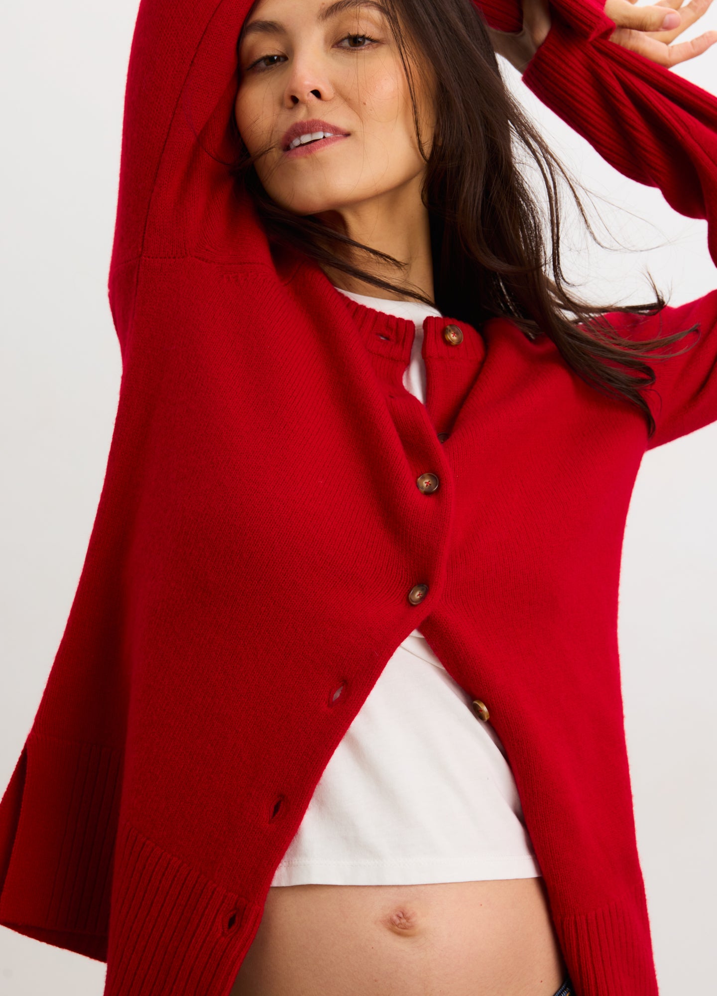 Red cashmere cardigan with front buttons and relaxed fit, styled over white top.