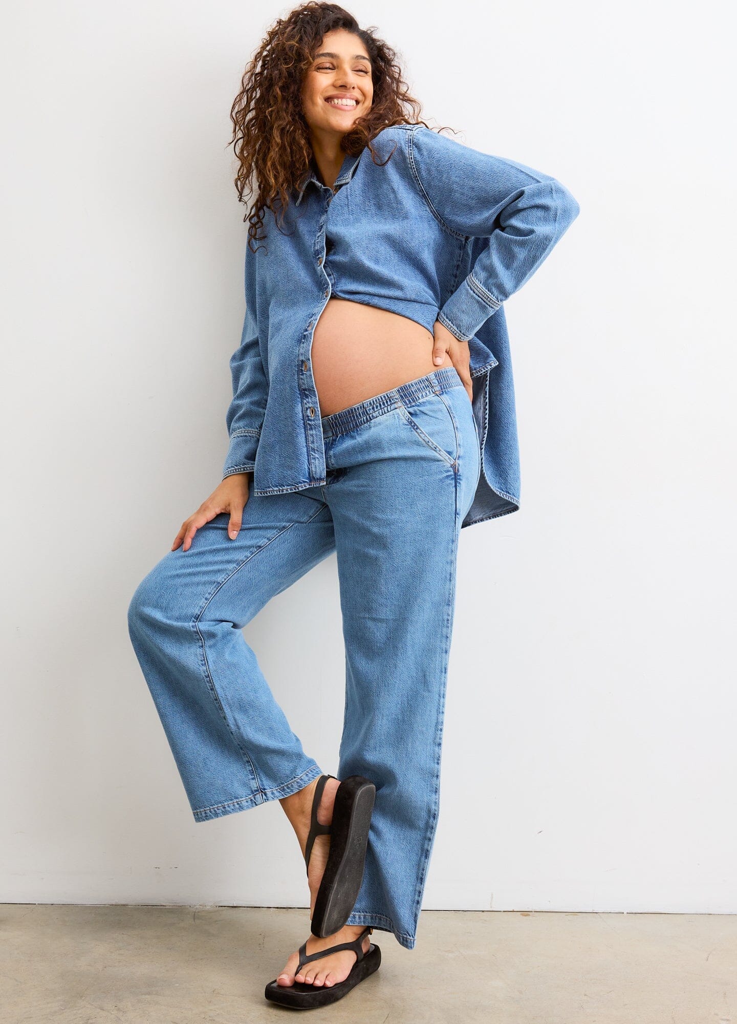 The Drapey Denim Boyfriend Shirt - Light blue soft denim maternity shirt unbuttoned to show pregnancy with long sleeves and relaxed fit for nursing and.