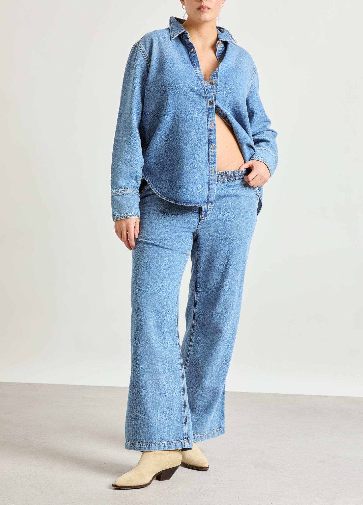 The Drapey Denim Boyfriend Shirt - Light blue soft denim maternity shirt unbuttoned to show pregnancy with long sleeves and relaxed fit for nursing and.