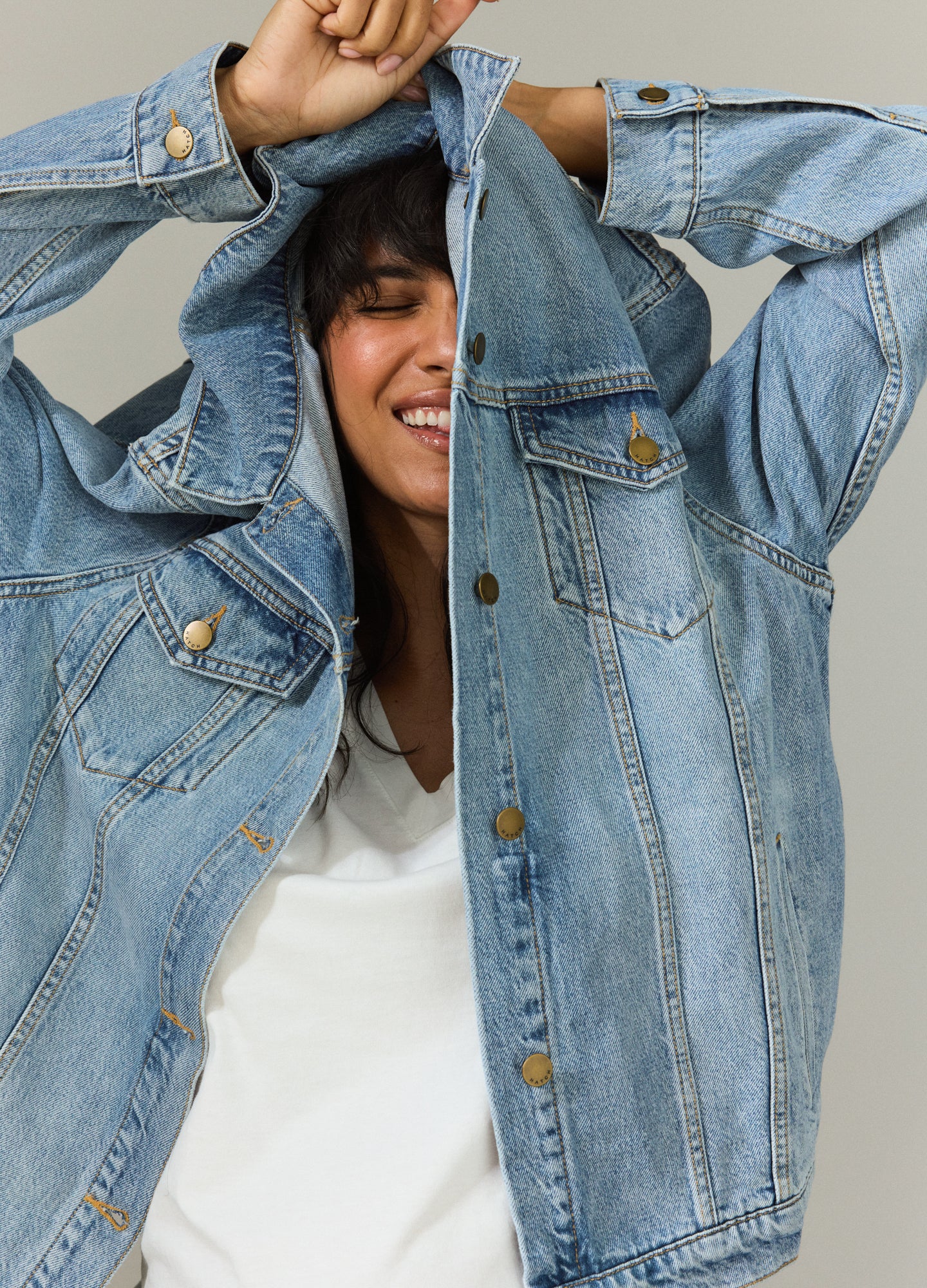Light wash maternity jean jacket with button front and chest pockets, worn by pregnant woman.
