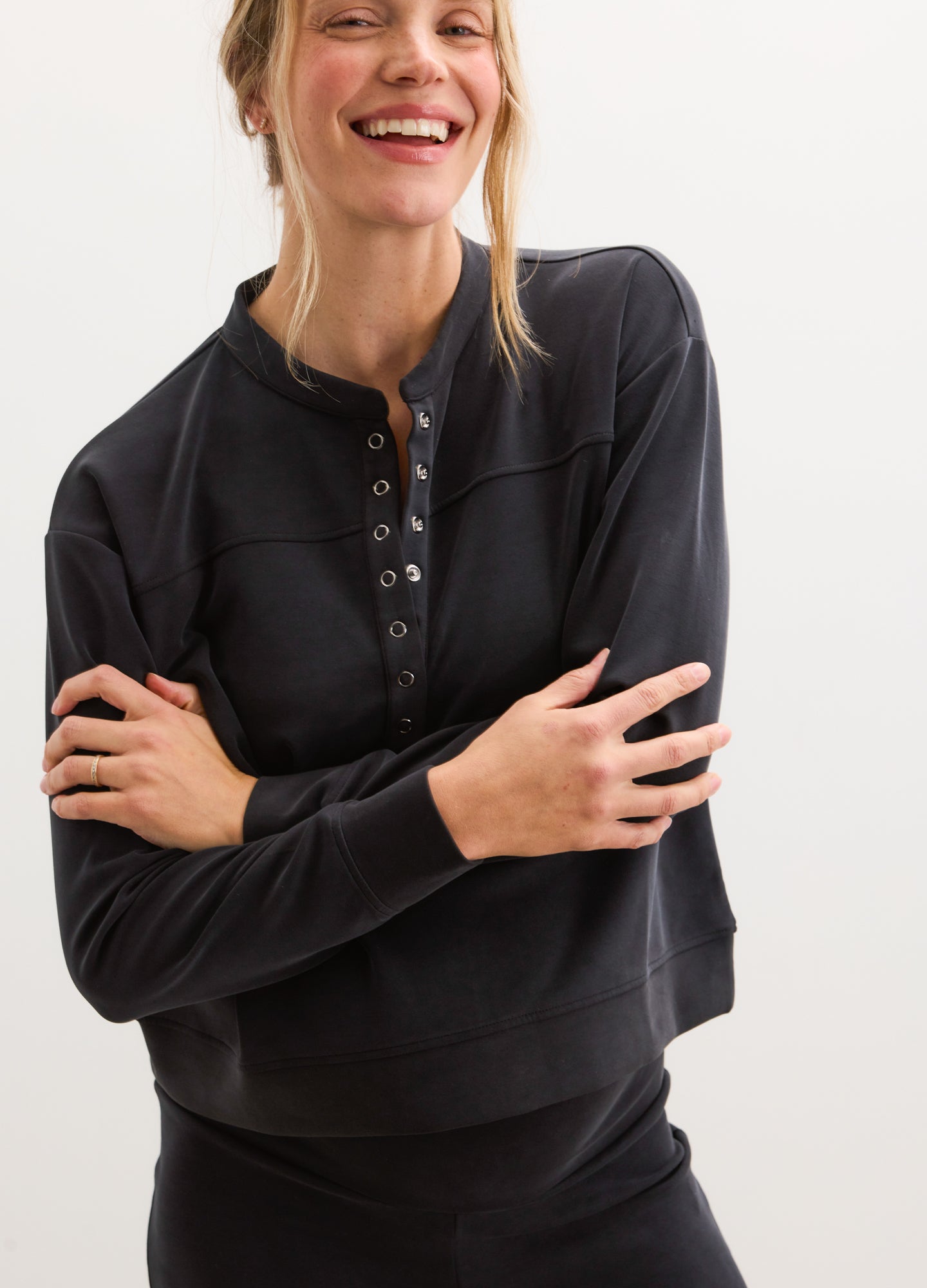 Black pullover with buttoned henley neckline, long sleeves, relaxed fit, soft knit fabric.