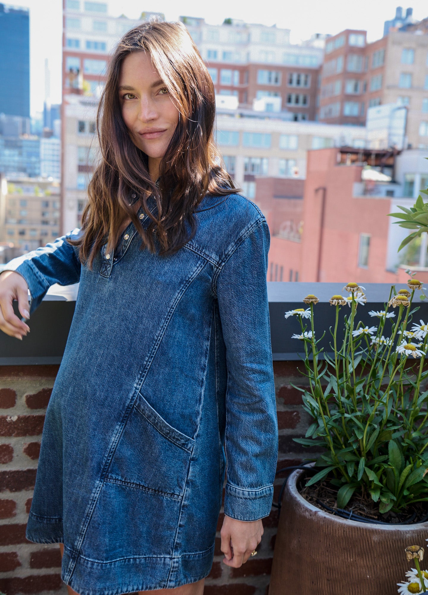 Blue drapey maternity denim mini dress with long sleeves and front pockets.