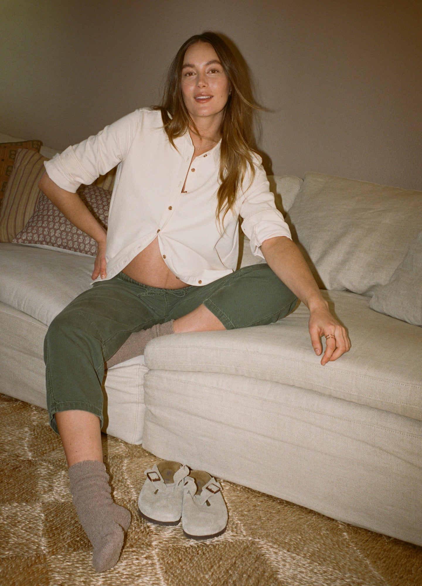 Light beige oversized denim boyfriend shirt styled open over pregnant belly, paired with olive green cropped pants and gray.