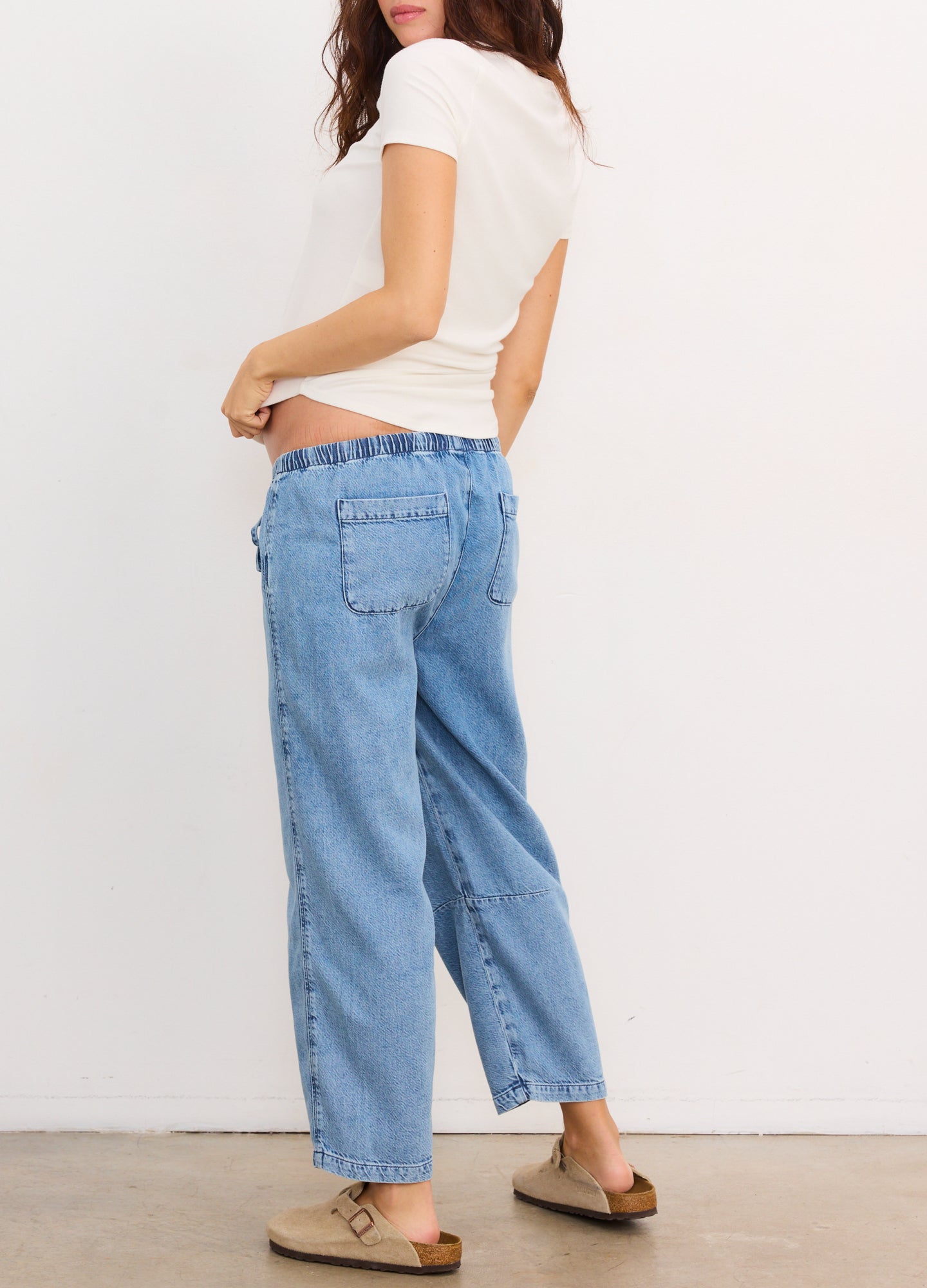 Light blue denim maternity barrel pants with side pockets and a relaxed fit, worn with a white top and sandals.
