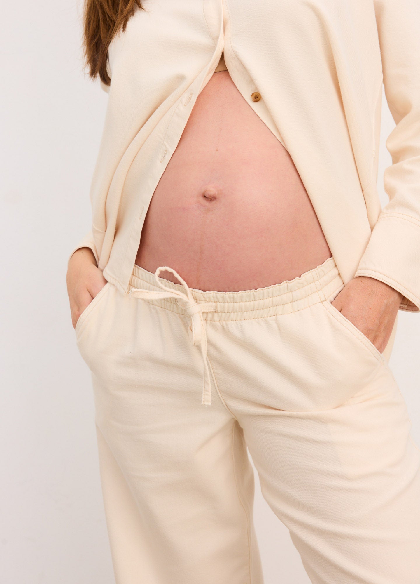 Cream-colored maternity wide-leg pants with soft, stretchy waistband and drawstring detail.