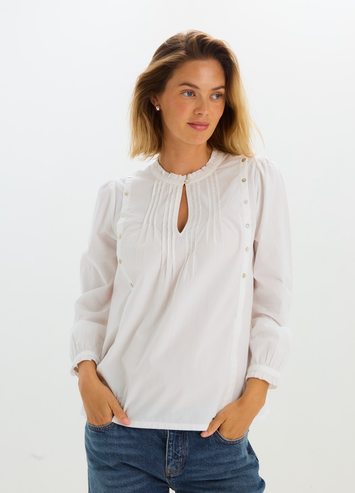 White maternity nursing blouse with long sleeves, keyhole neckline, and delicate pleated detailing.