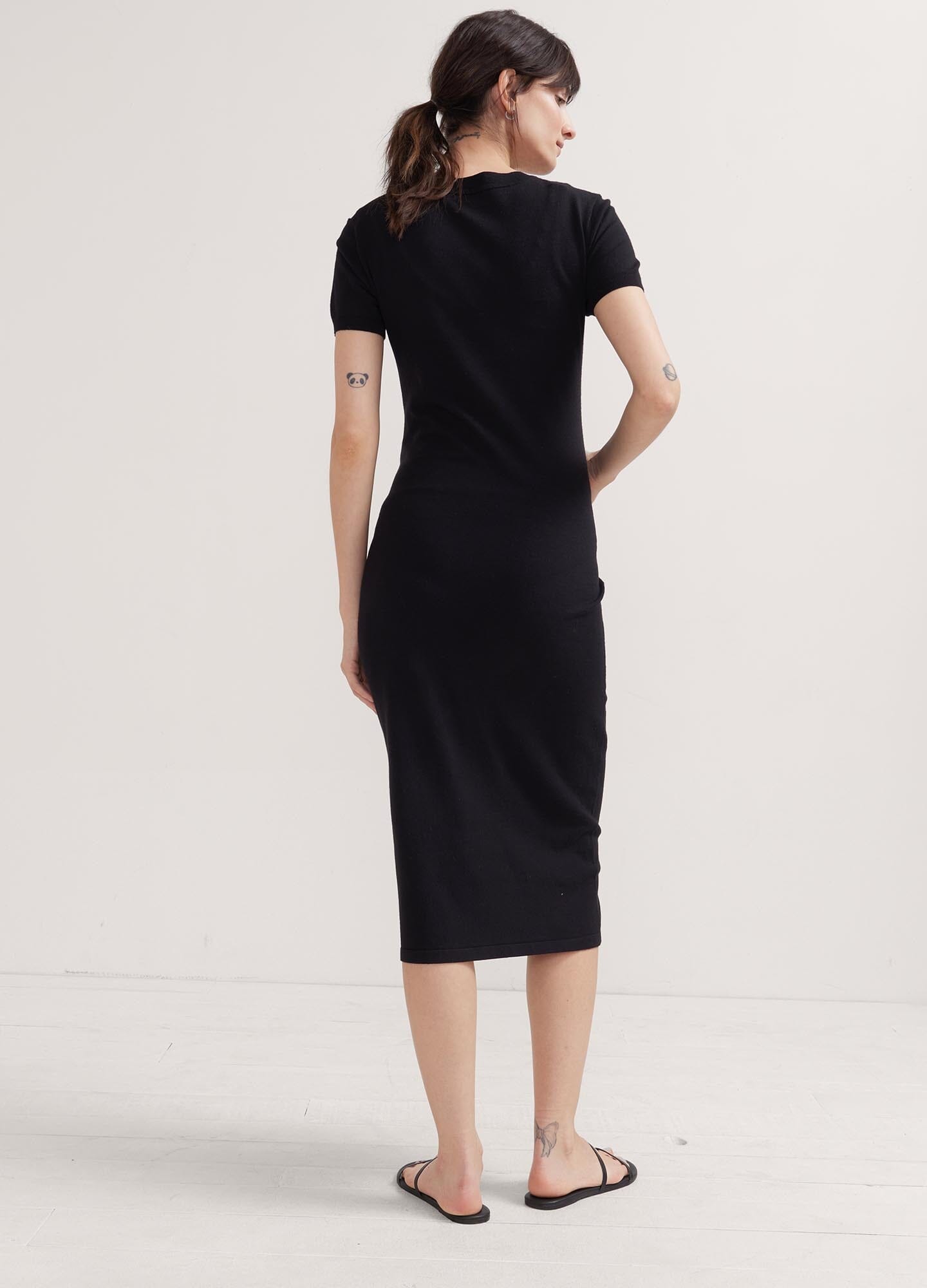 The Eliza Dress POS - Black short-sleeve maternity dress with nursing-friendly design and fitted silhouette, styled with tall black boots.