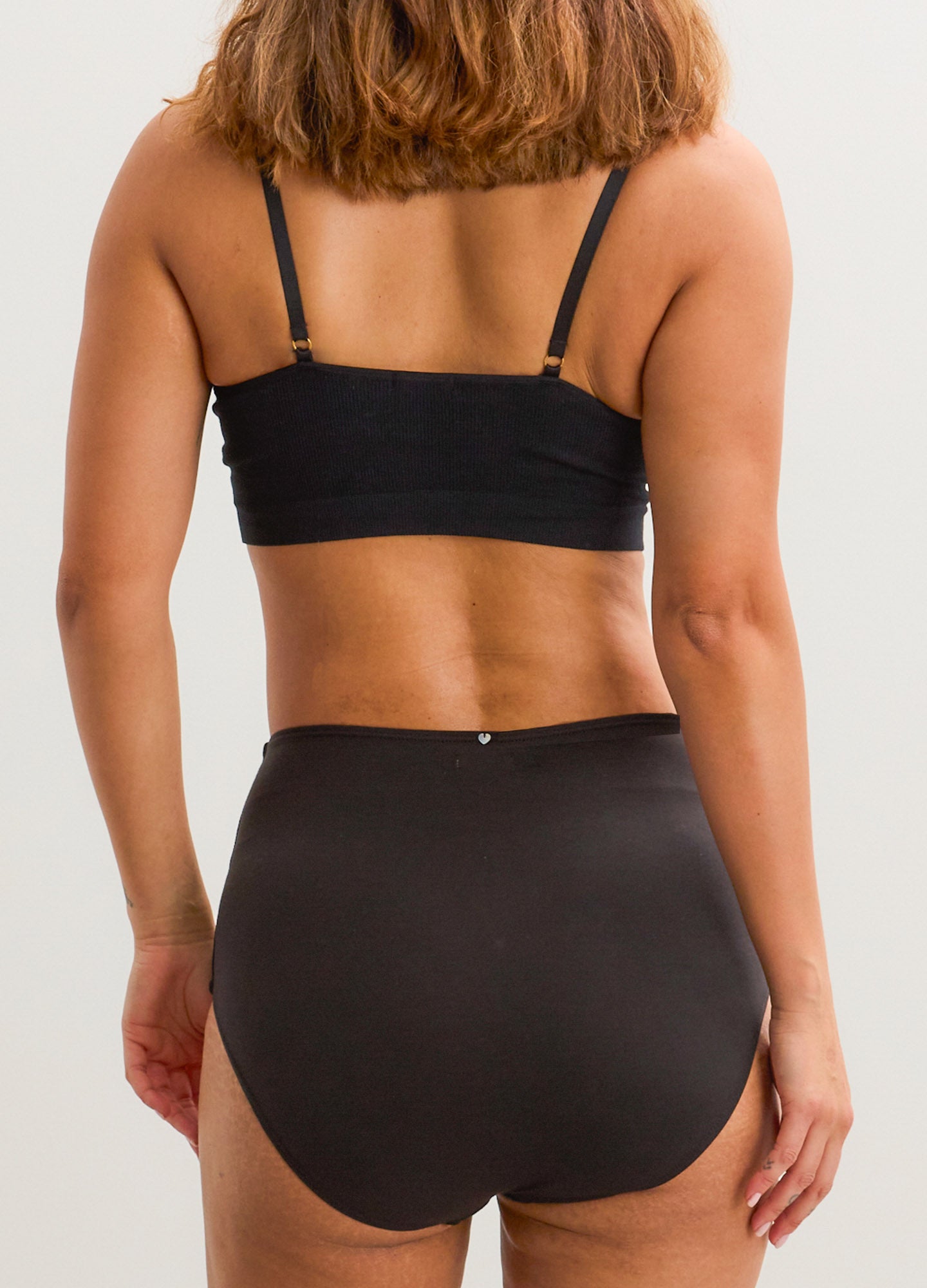 Black nursing bra with adjustable straps paired with high-waist black maternity briefs.