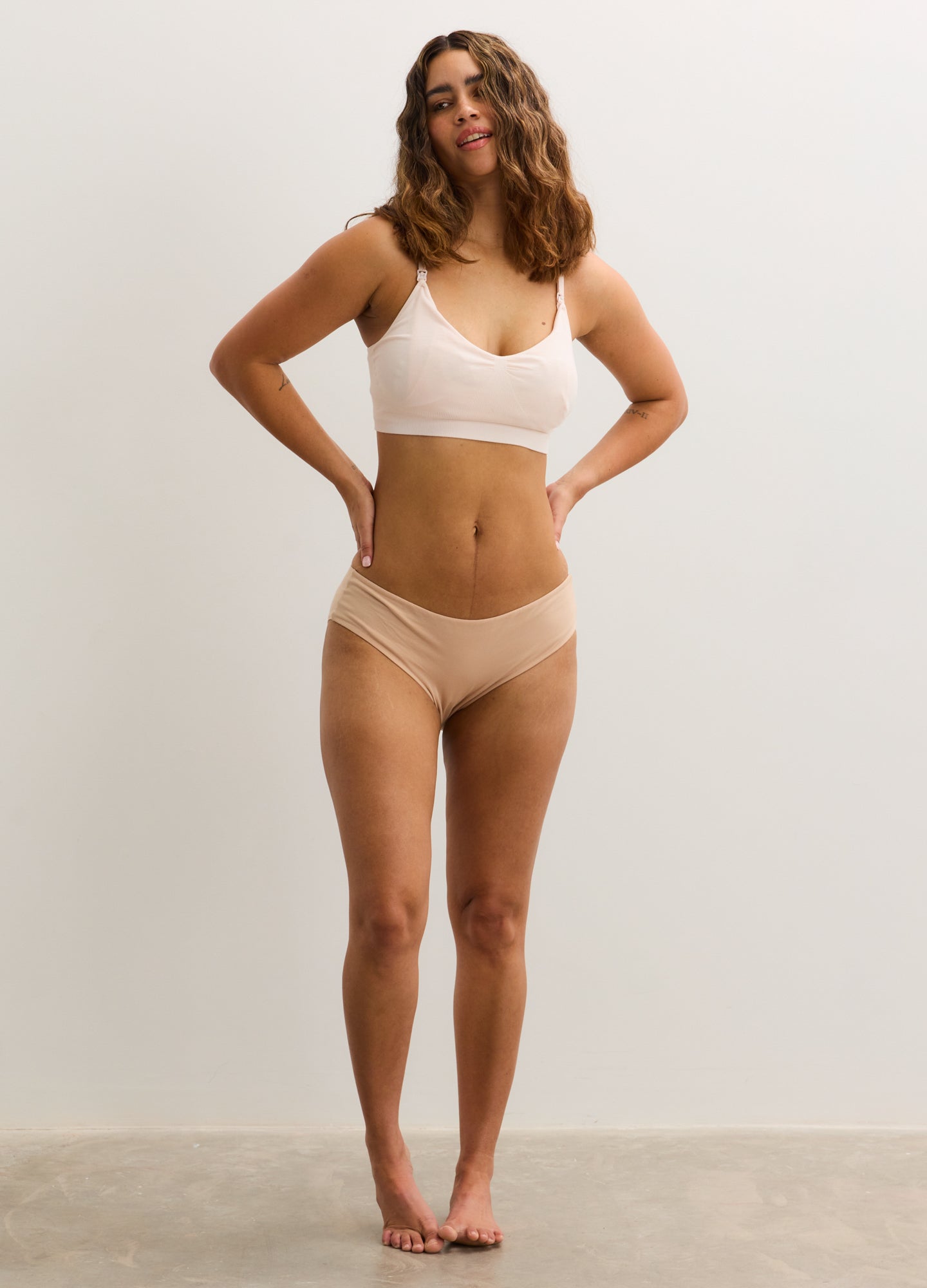 Nude seamless maternity nursing bra with adjustable straps and supportive fit.