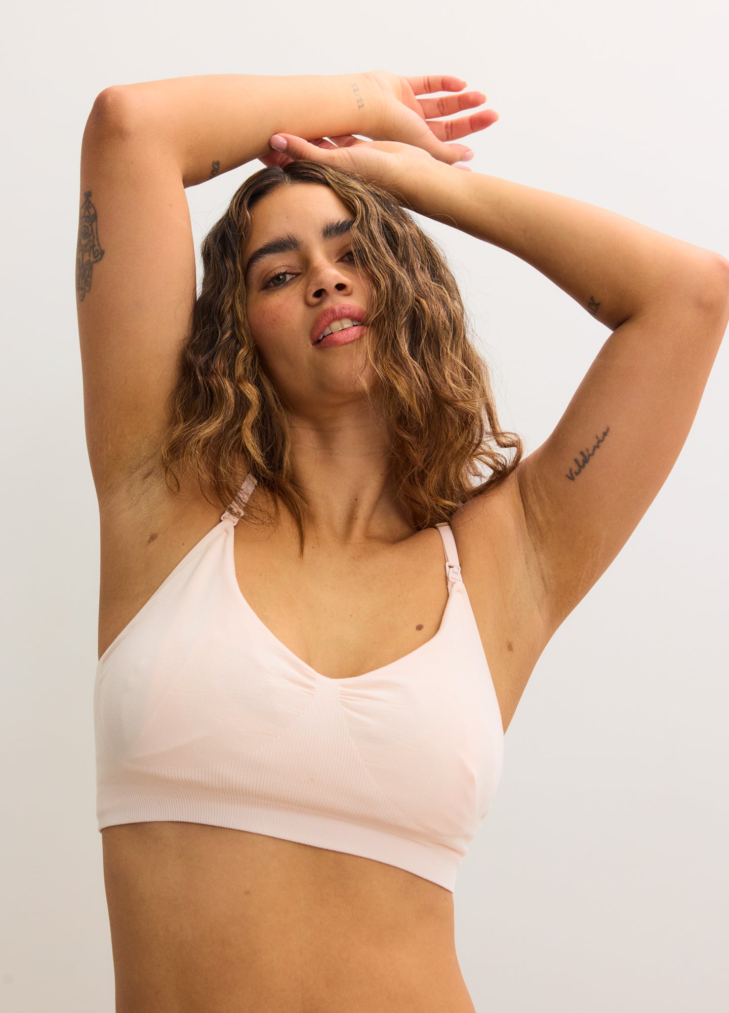 Soft pink nursing and pumping bra with wide straps and seamless cups on a model.