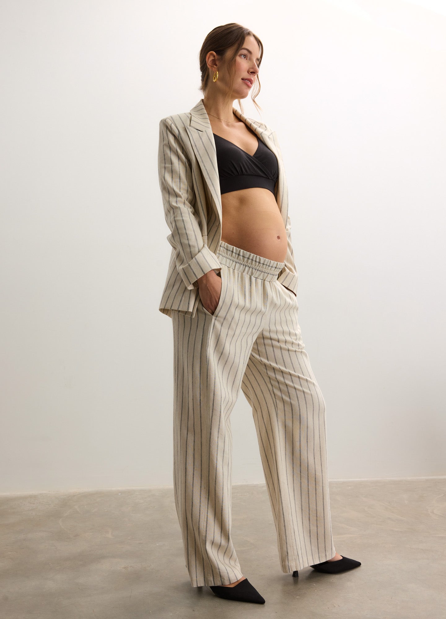 Cream and beige striped maternity pants with a relaxed fit, worn with a matching blazer and black cropped top.