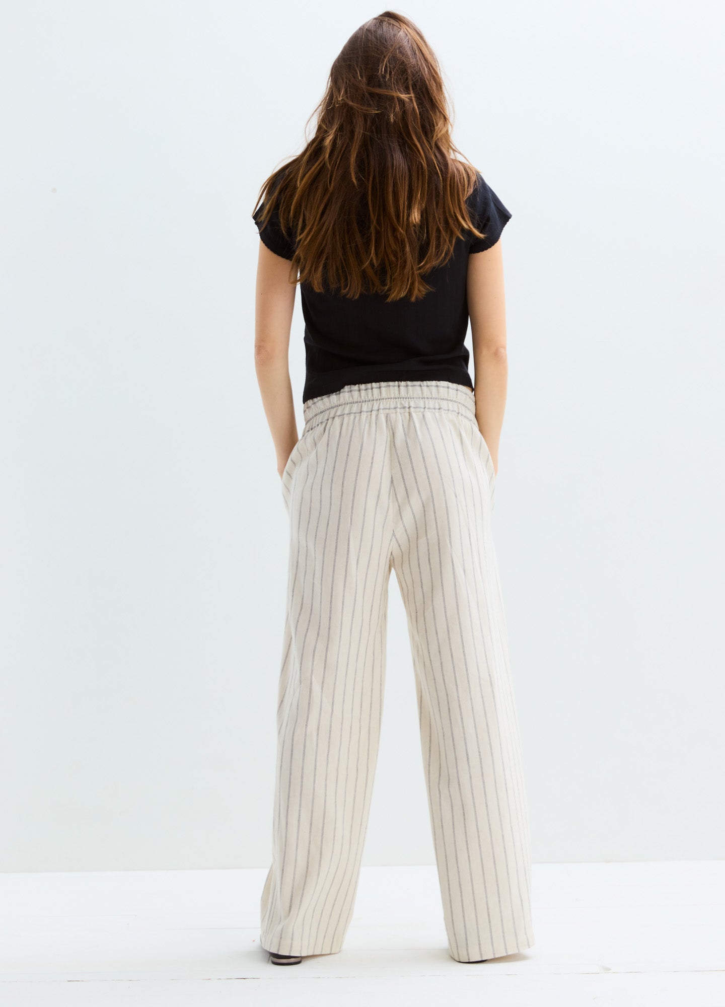 Beige wide-leg maternity pants with thin vertical stripes and adjustable waistband.