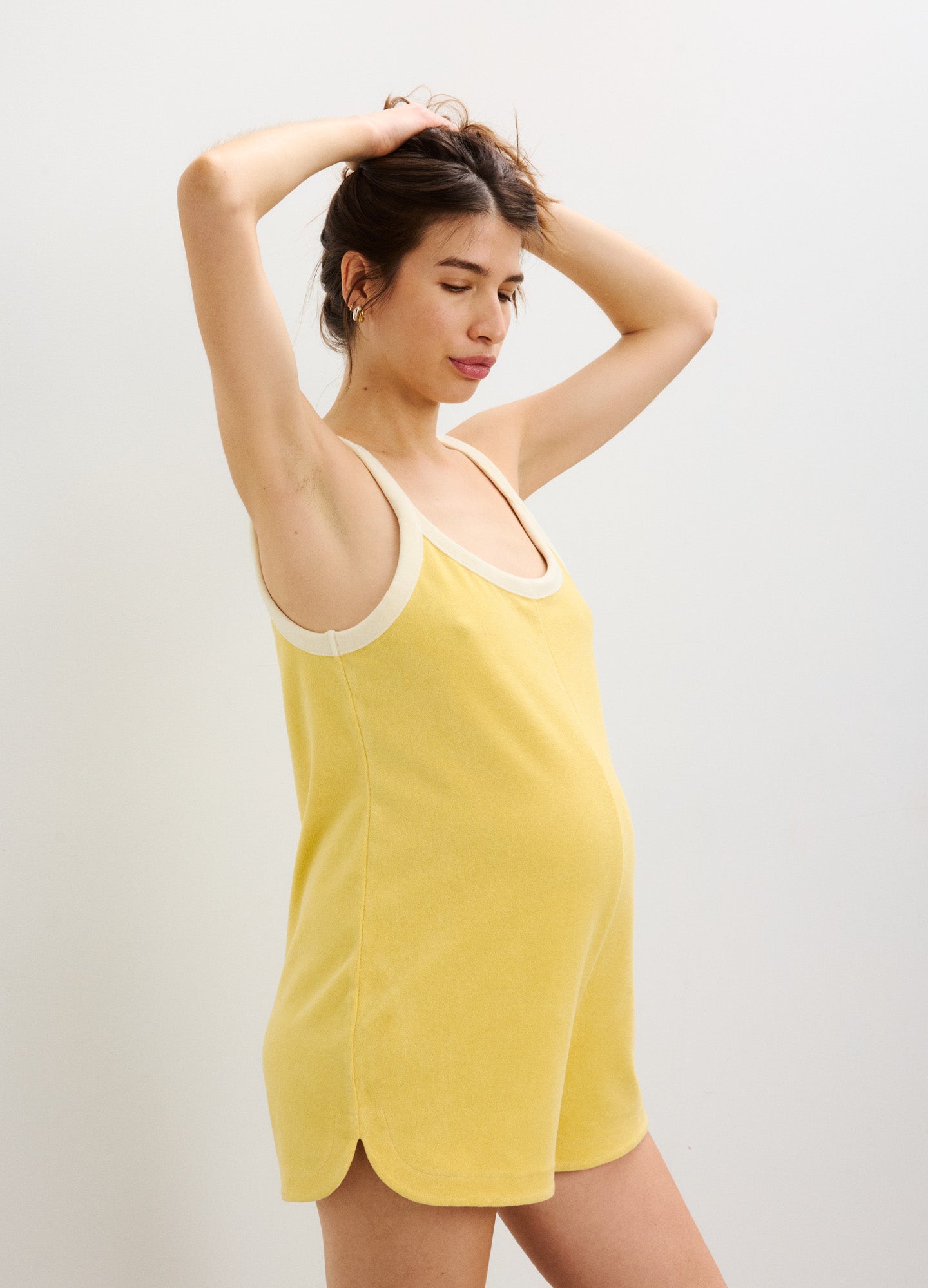 Soft yellow sleeveless maternity romper with scoop neckline and curved hemline, designed for pregnancy comfort.