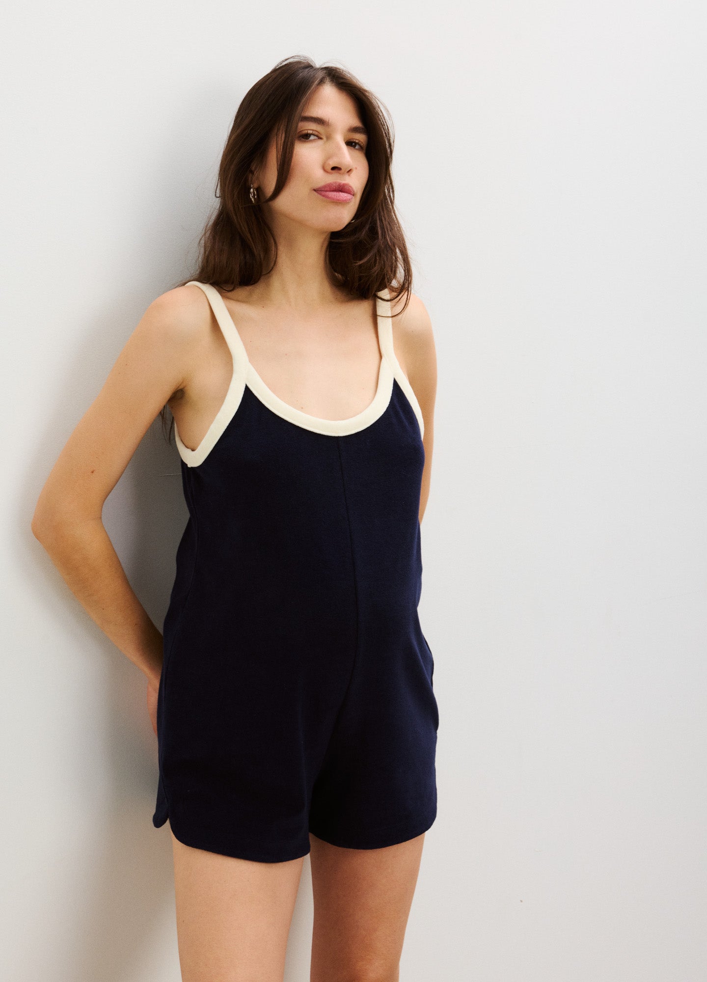 Navy blue sleeveless maternity romper with cream trim, fitted around baby bump, soft knit fabric.