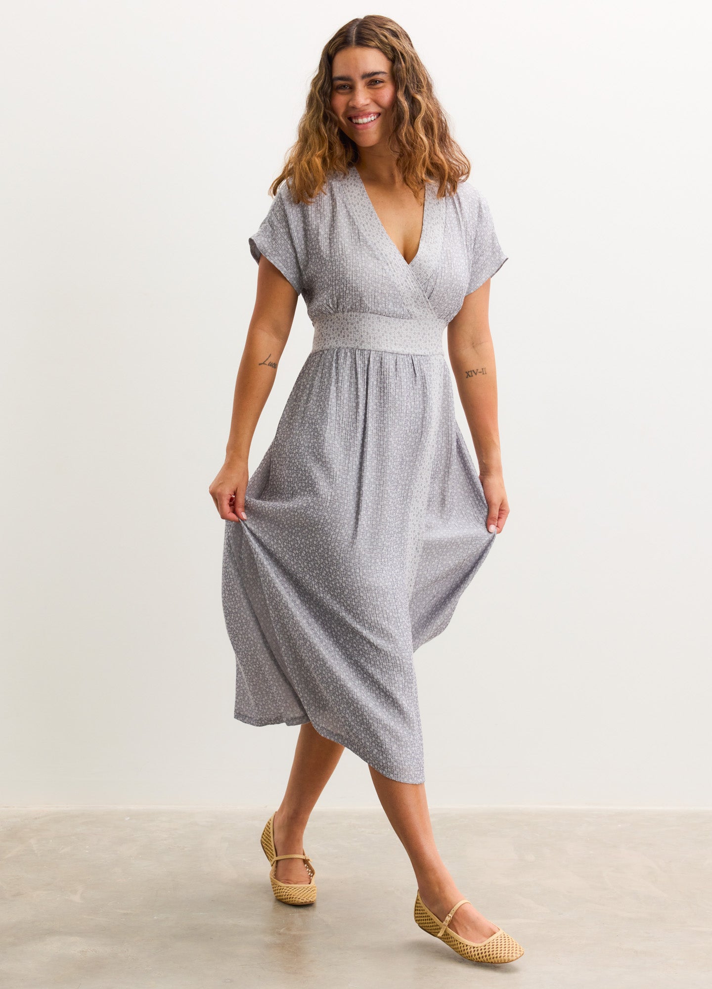 Light gray maternity dress with V-neck, short sleeves, and gathered empire waist, midi length.