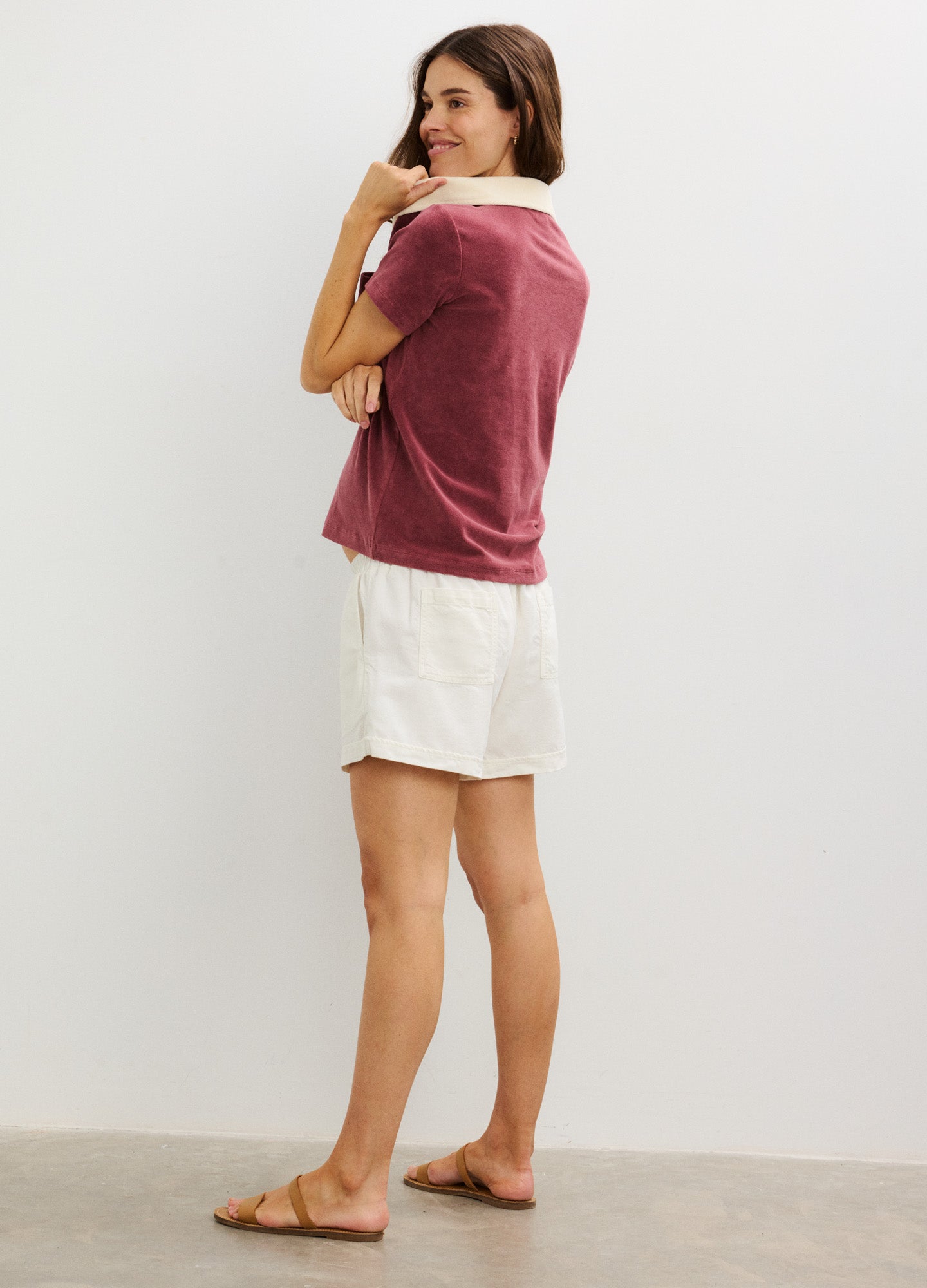 Maternity polo top in dusty rose with white collar and short sleeves paired with white shorts.