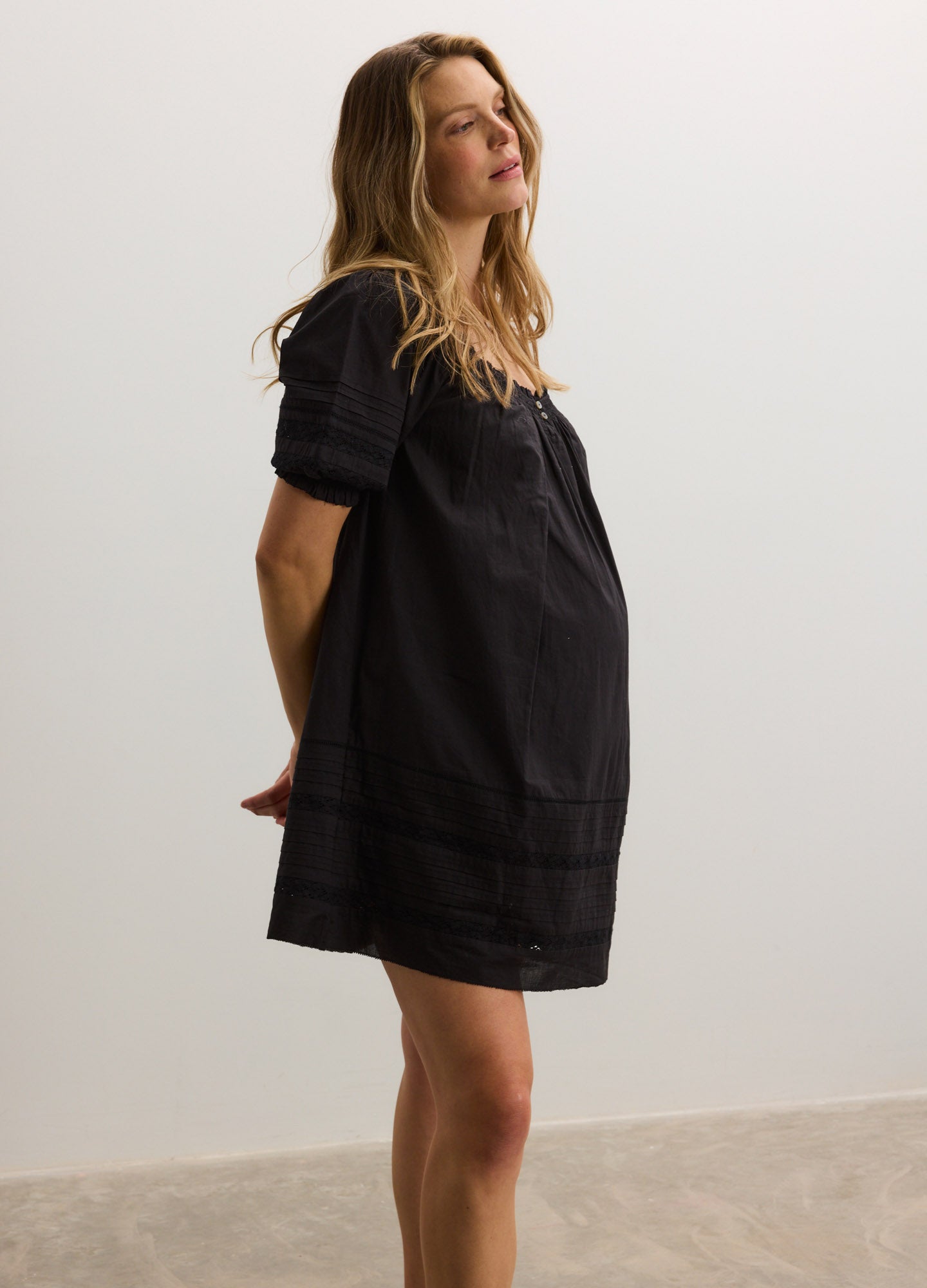 Black short-sleeve maternity nursing mini dress with loose fit and lace trim detailing.