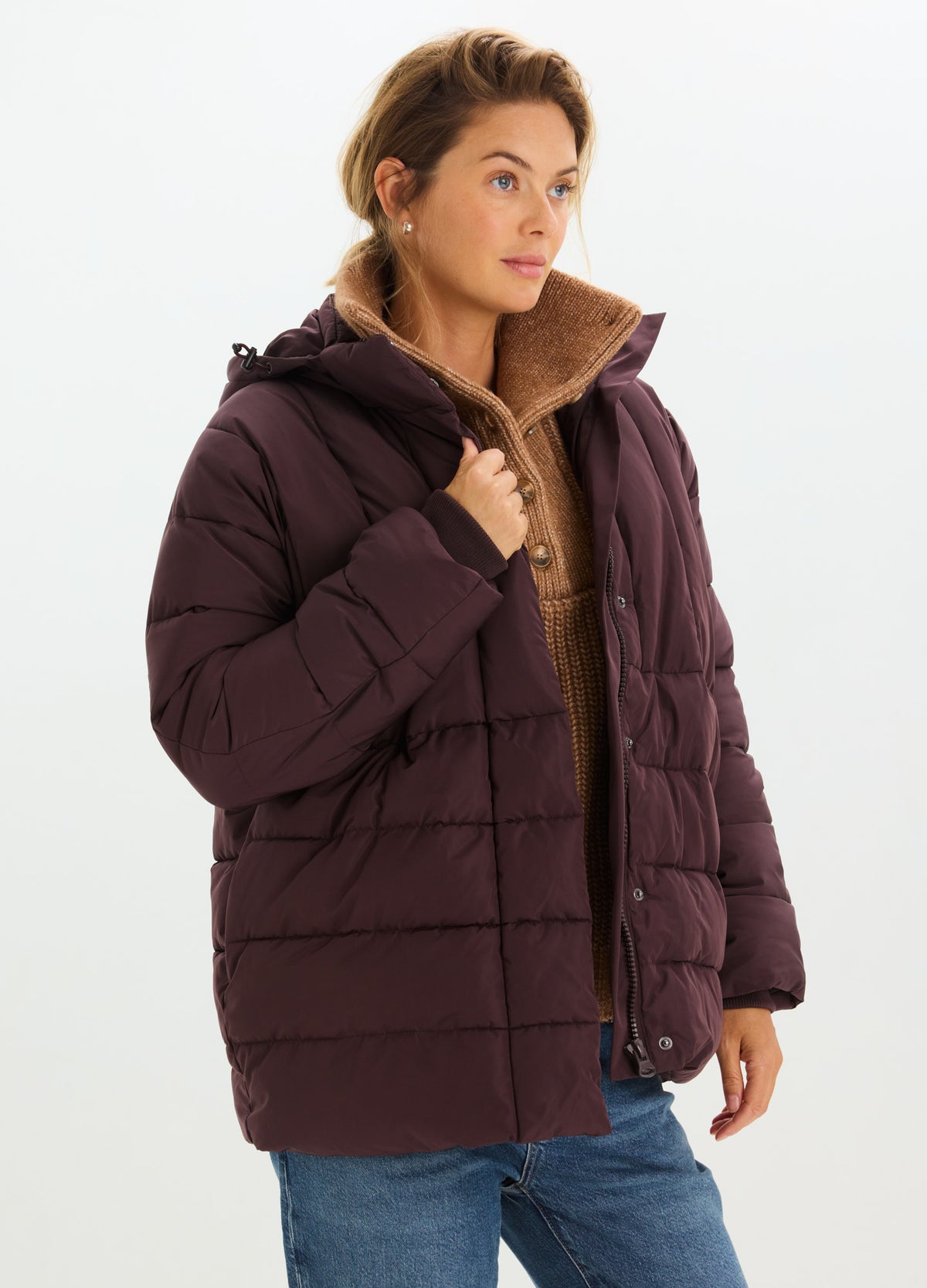 Woman wearing a dark plum quilted puffer jacket with a high collar and brown fleece lining.