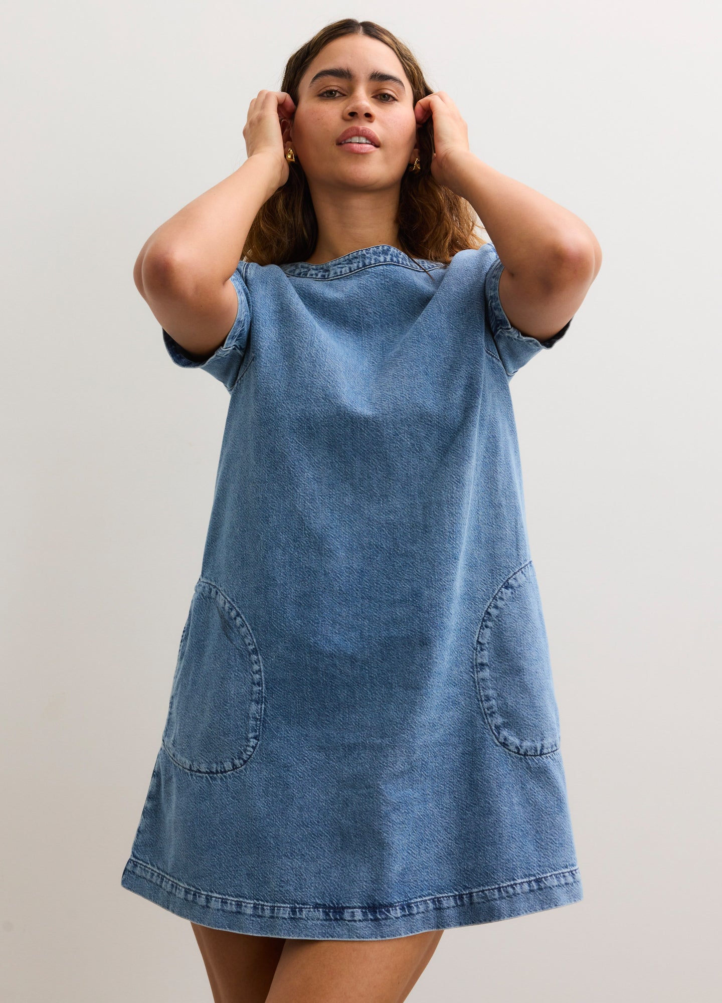 Light blue maternity denim dress with short sleeves, round neckline, and front patch pockets.