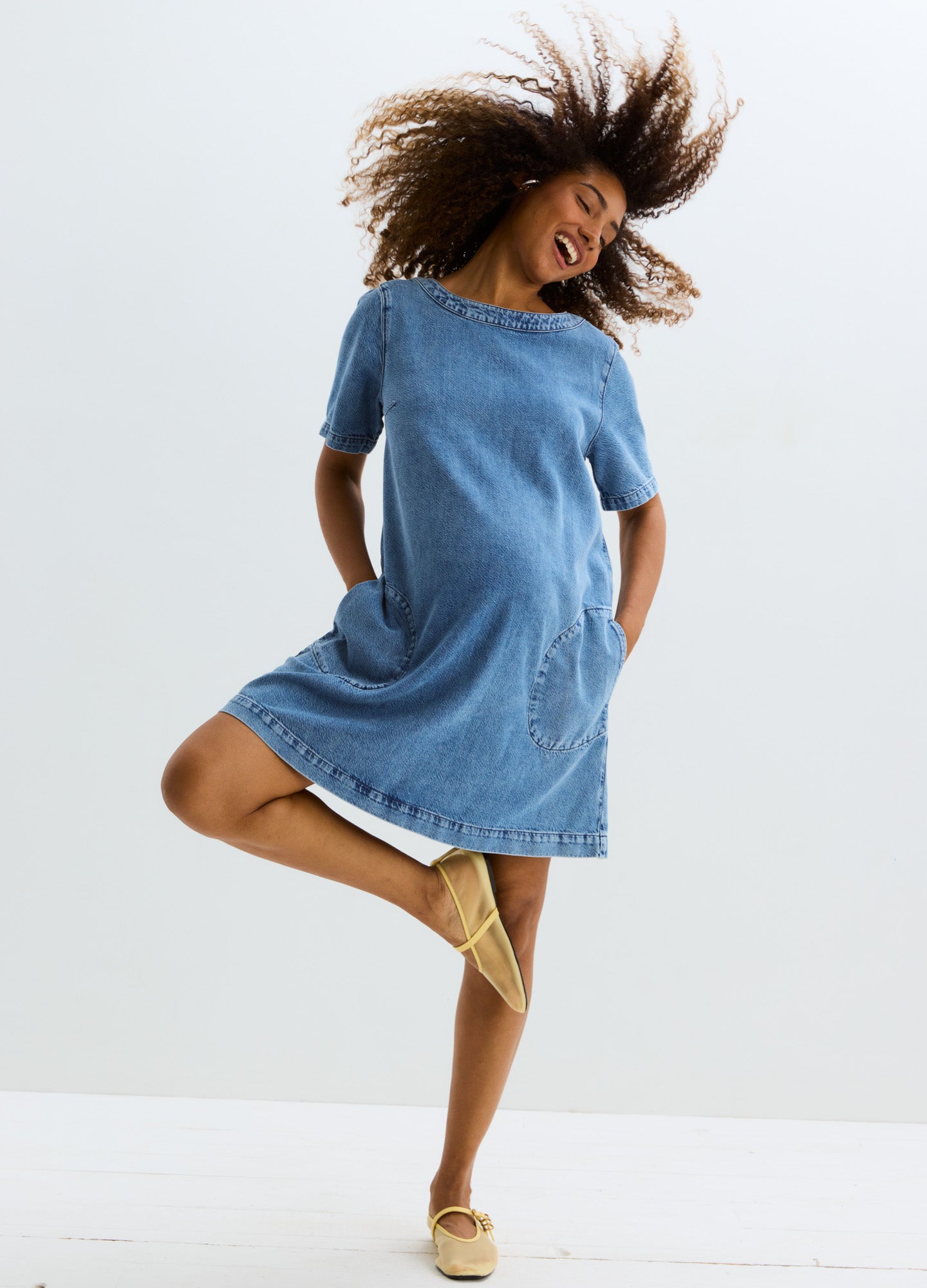 Blue denim maternity dress with short sleeves, round neckline, and front pockets, above-knee length.