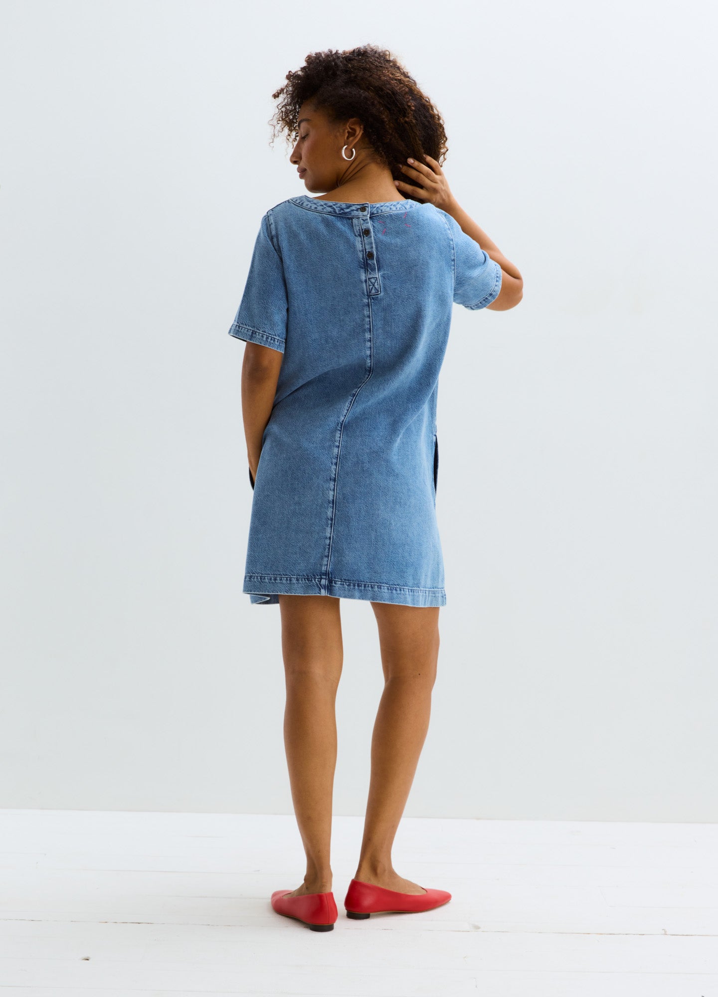 Light blue denim maternity dress with short sleeves, back button closure, and knee-length hem.