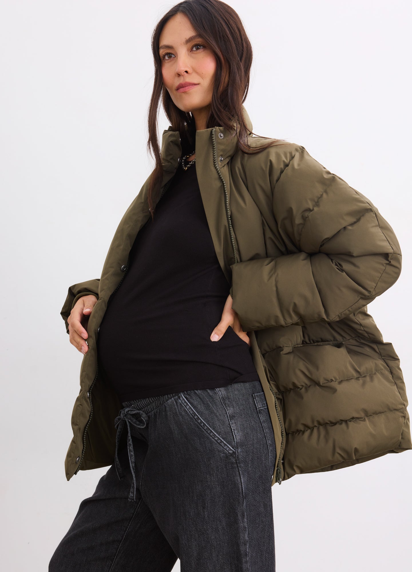 Olive maternity puffer jacket with high collar and quilted design worn by pregnant woman.