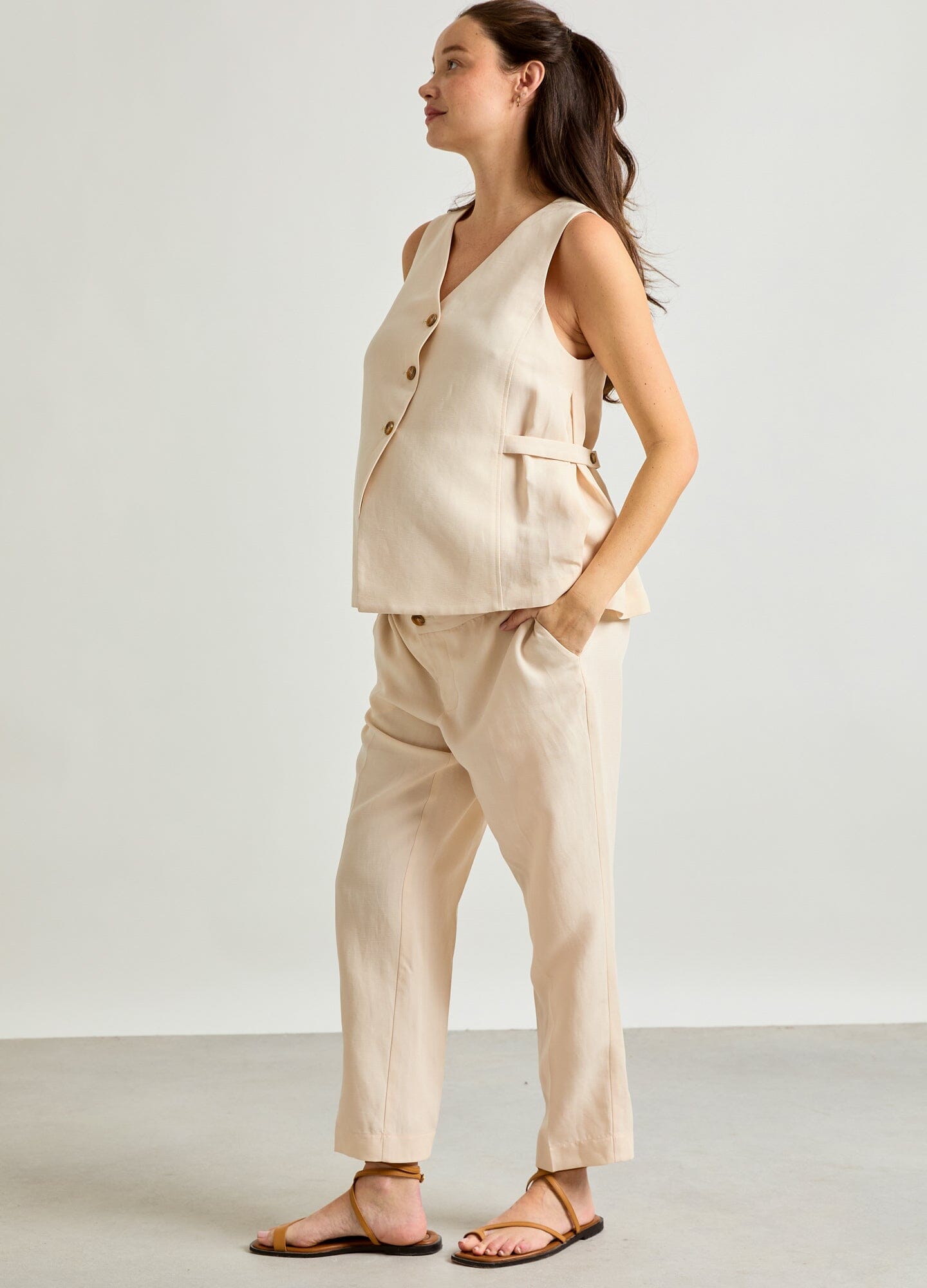 The Nadia Vest - Black sleeveless maternity vest with buttons and side pockets, designed for pregnancy, nursing, and postpartum.