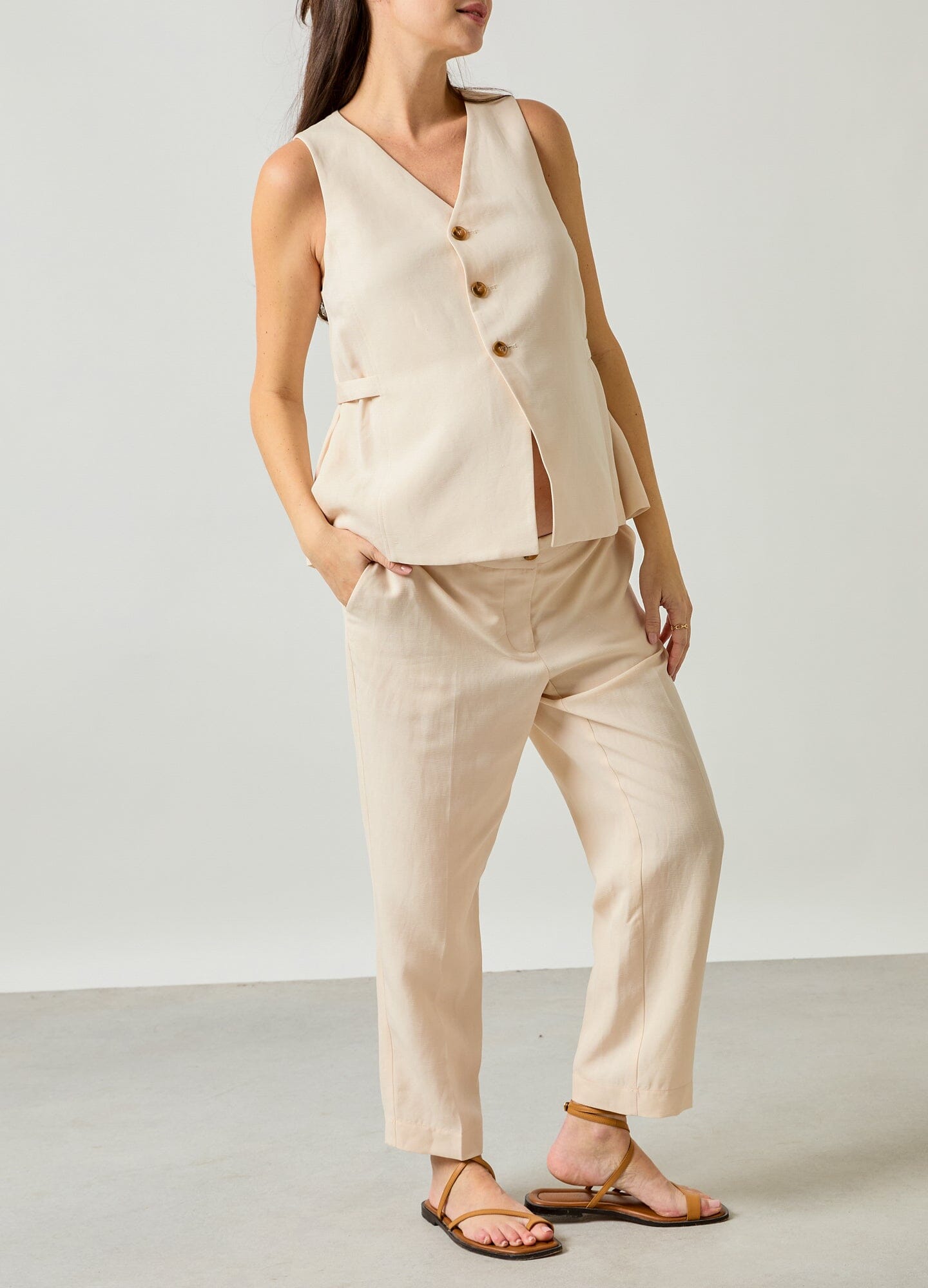 The Nadia Vest - Black sleeveless maternity vest with buttons and side pockets, designed for pregnancy, nursing, and postpartum.