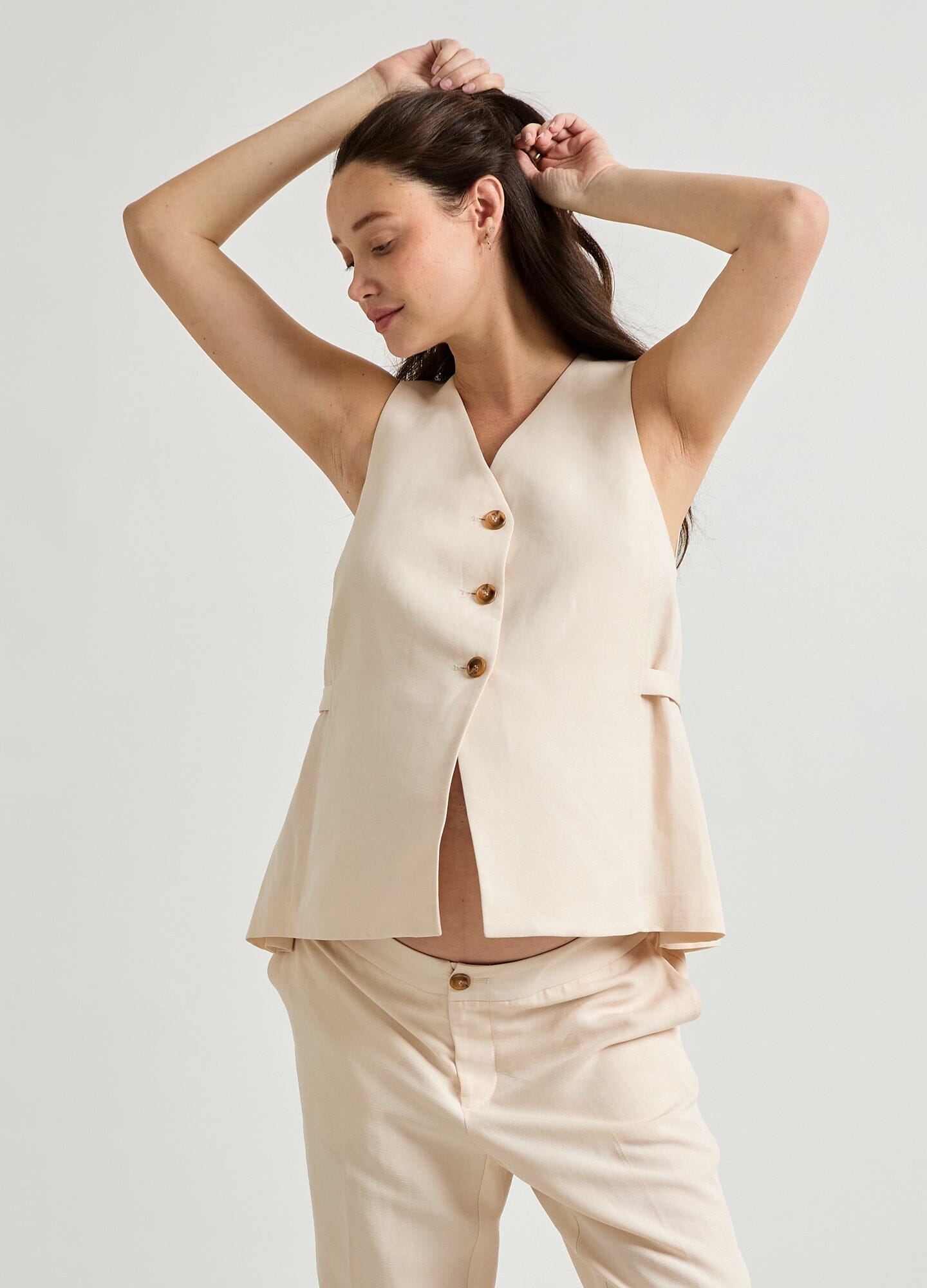 The Nadia Vest - Black sleeveless maternity vest with buttons and side pockets, designed for pregnancy, nursing, and postpartum.