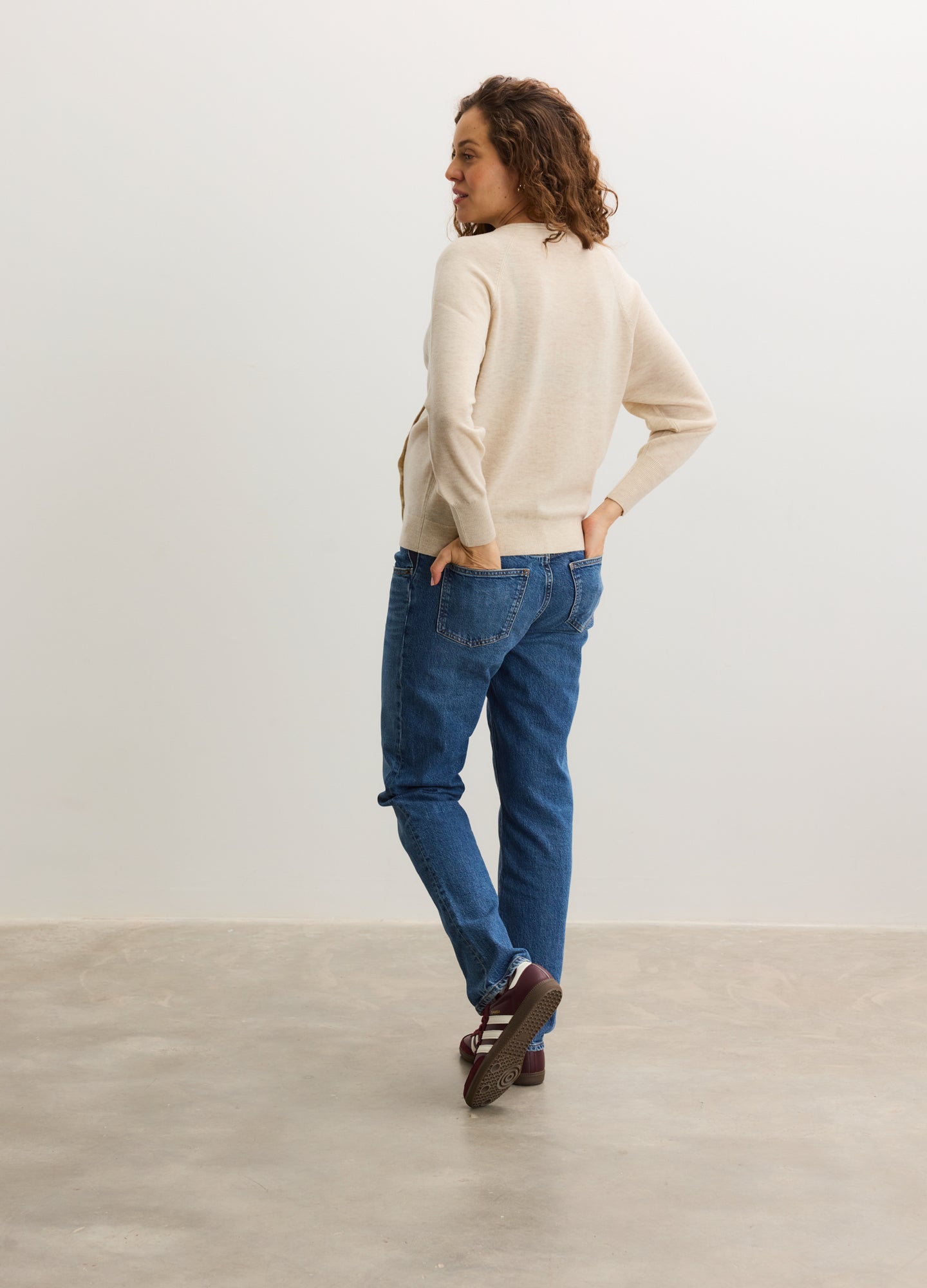 Cream-colored maternity cardigan with long sleeves, soft fabric, and relaxed fit paired with blue jeans.