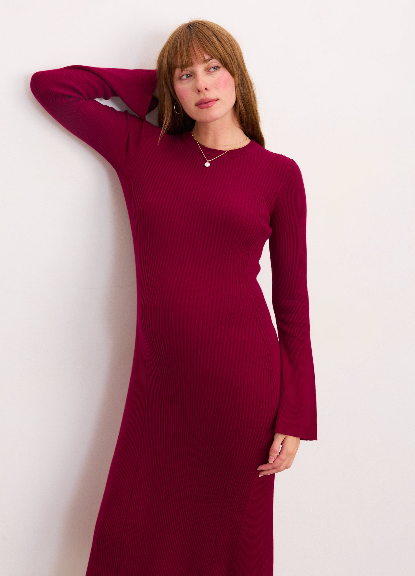 Burgundy ribbed midi dress with long sleeves and flared cuffs, designed for maternity wear.