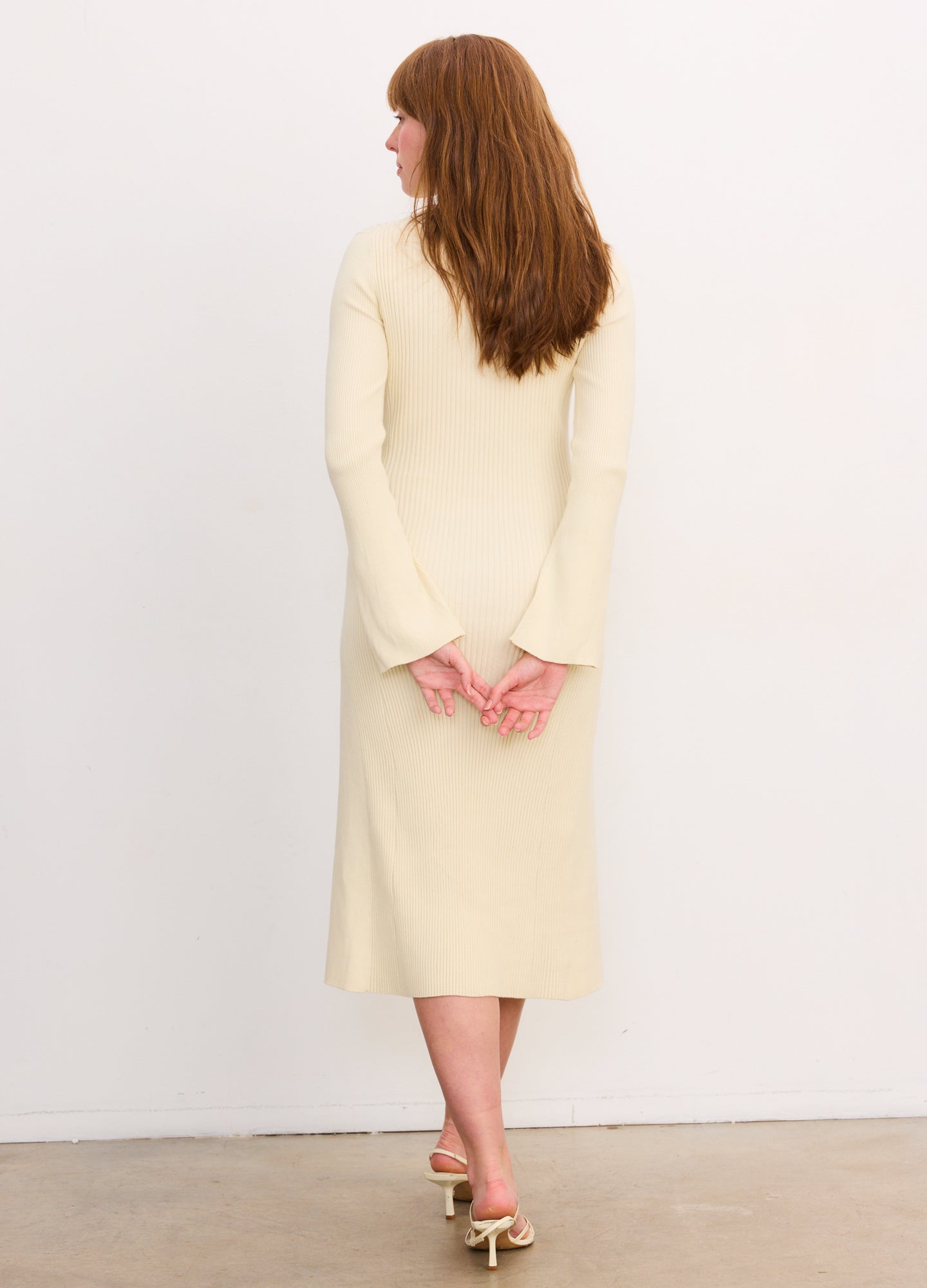 Cream-colored ribbed midi knit dress with long flared sleeves, fitted silhouette for maternity wear.