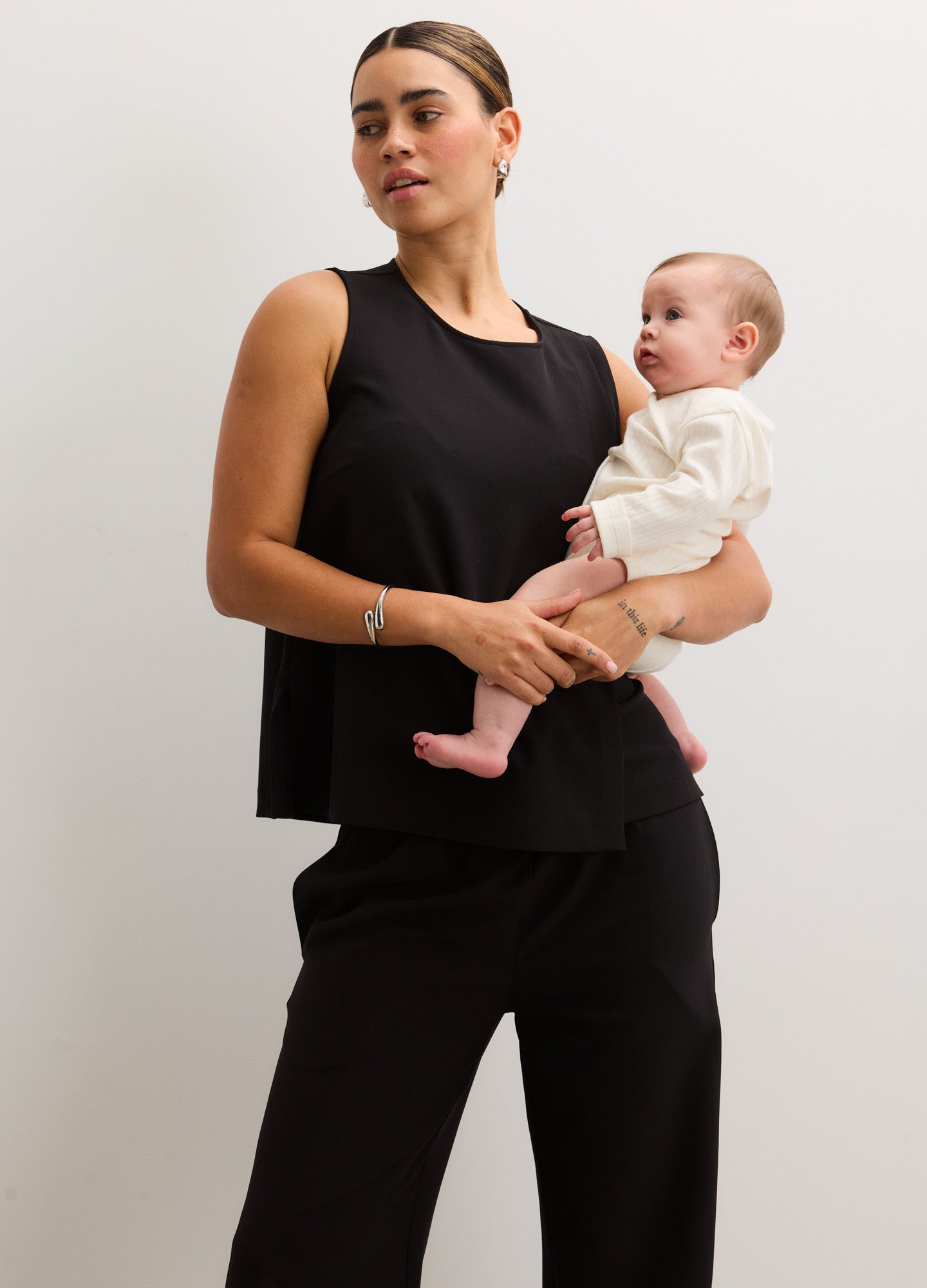 Black sleeveless nursing tank with scoop neck paired with matching maternity pants, soft stretch fabric.