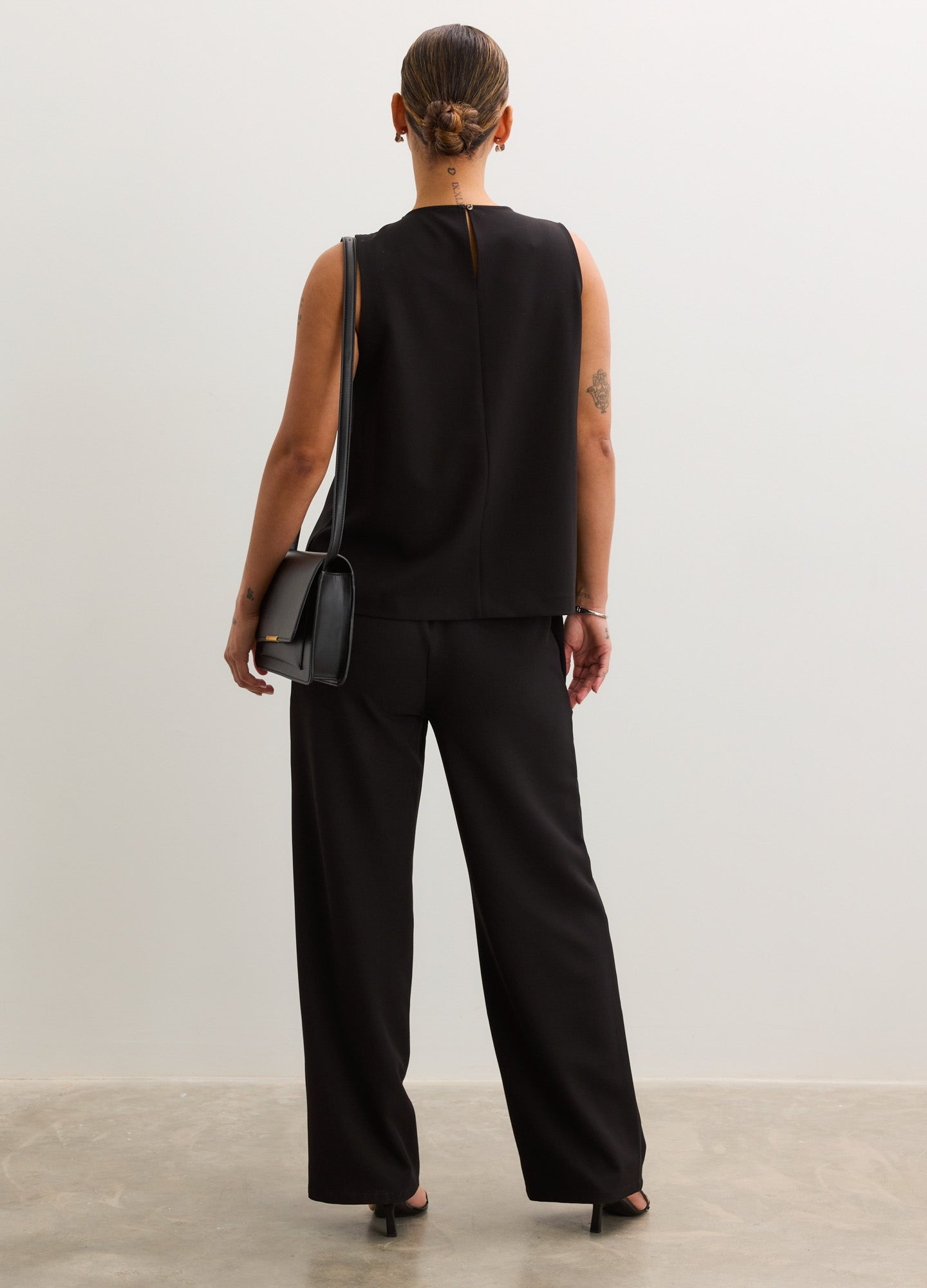 Black sleeveless nursing tank top with a relaxed fit, paired with matching loose black pants.