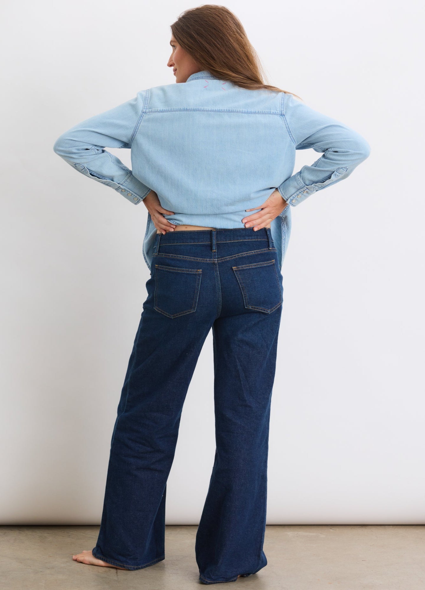 Dark blue wide-leg maternity jeans with back pockets, worn with a light blue denim shirt.