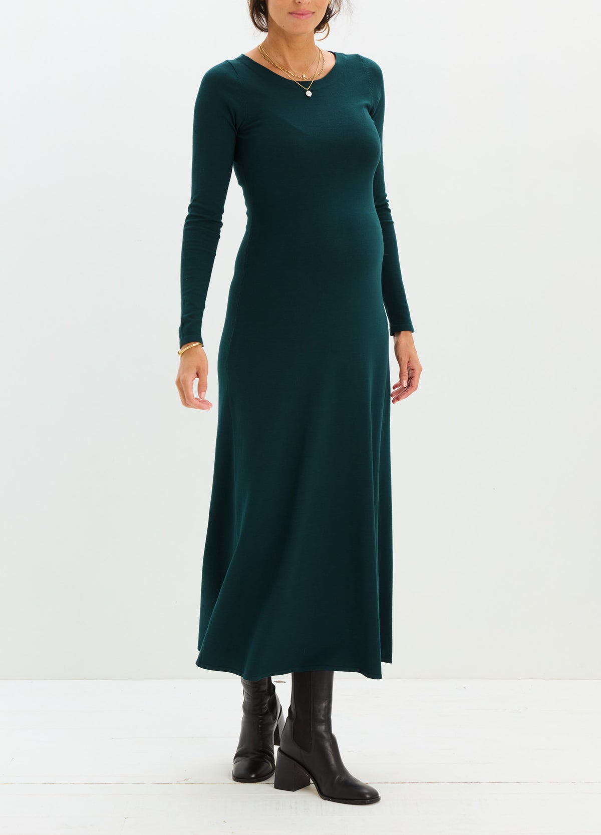 Dark green maternity knit dress with long sleeves and fitted silhouette paired with black ankle boots.