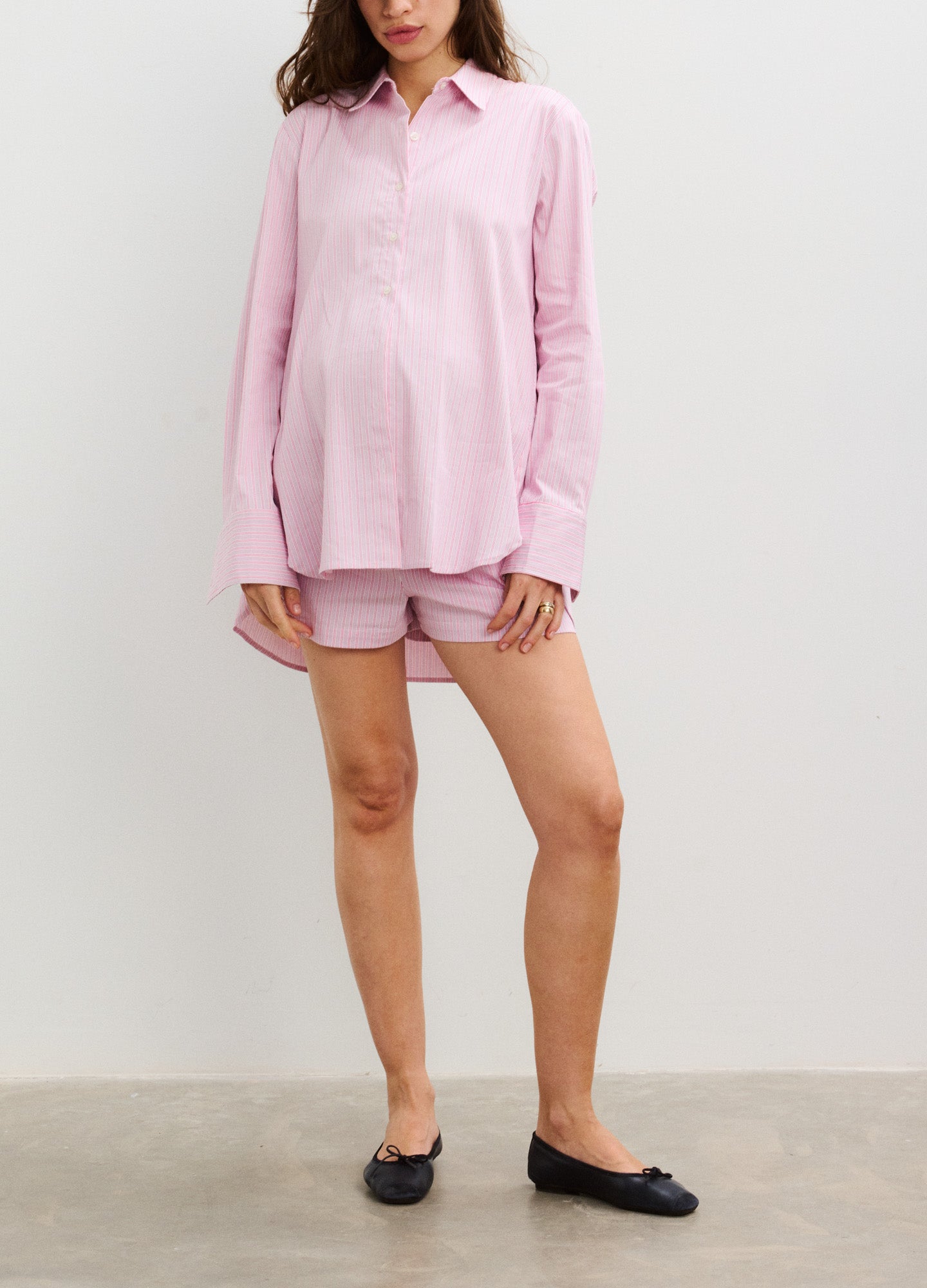 Soft pink maternity shorts with adjustable side ties paired with a matching long-sleeve collared top.