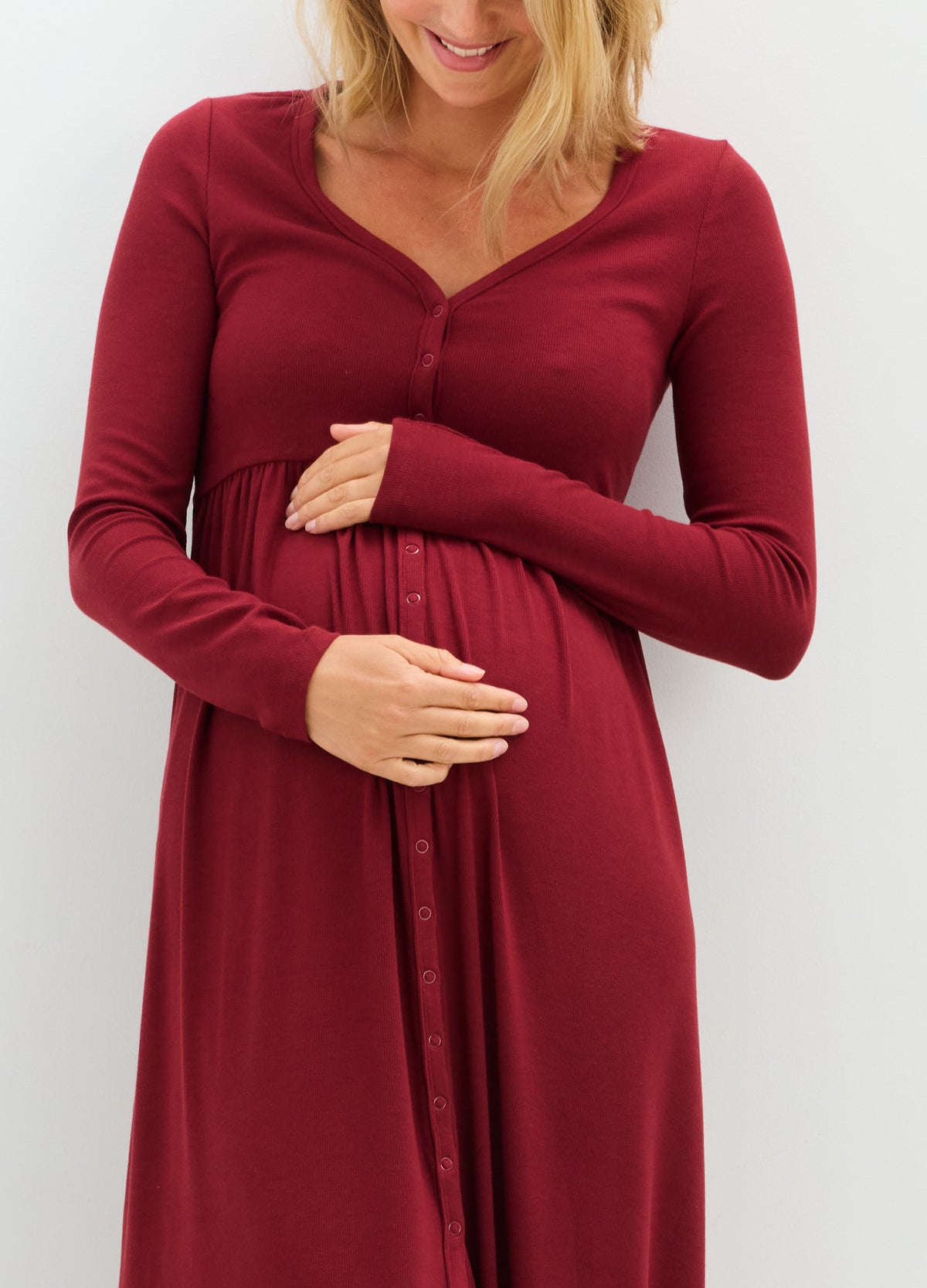 Long-sleeve maternity dress in soft ribbed fabric with deep red color and nursing-friendly wrap neckline.