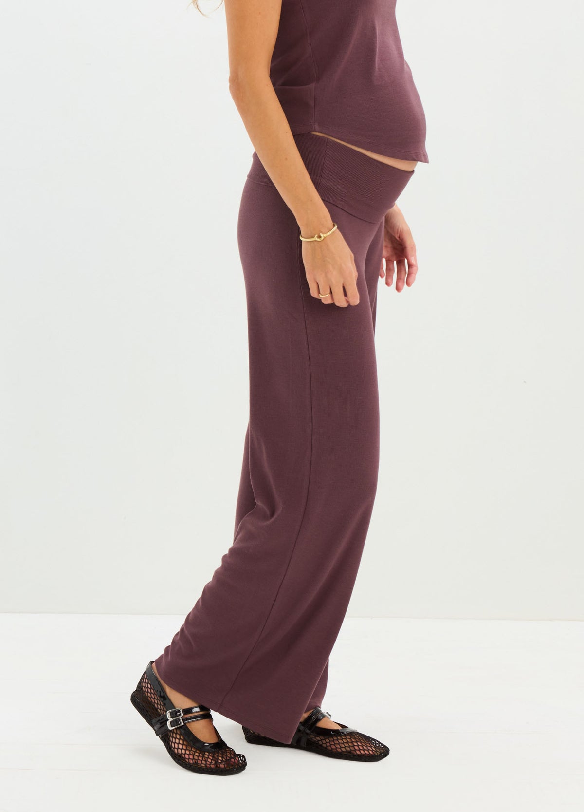 Plum-colored ribbed maternity pants with relaxed fit and full length waistband over baby bump.
